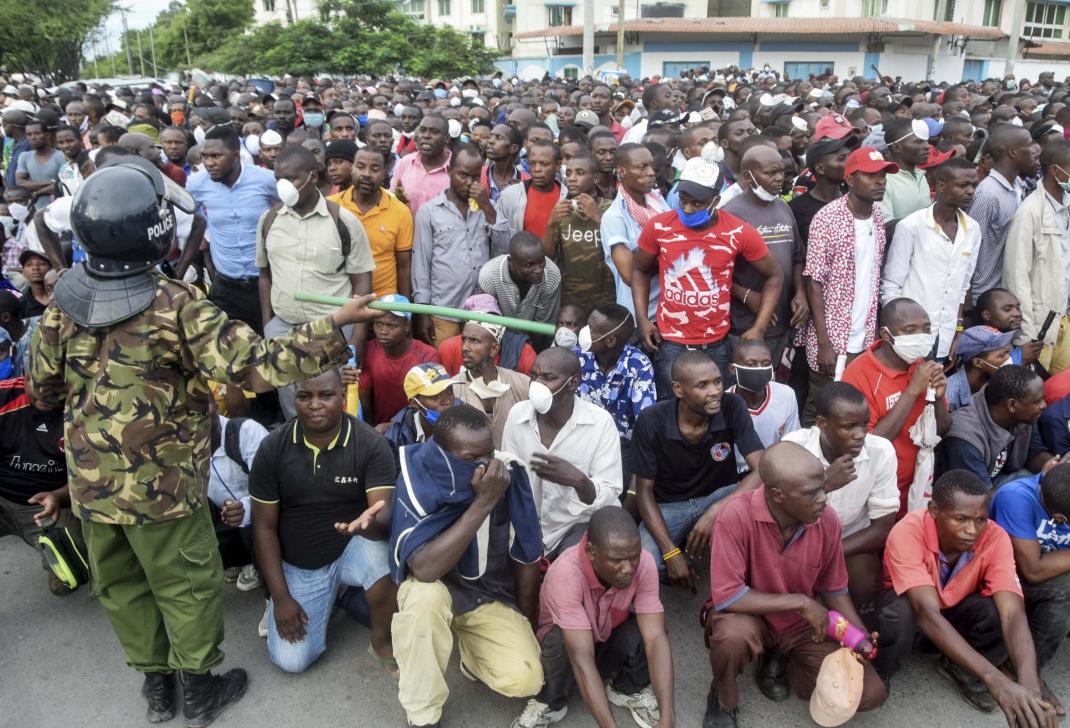 Kenyan police hold back ferry passengers causing a crowd to form outside the ferry in Mombasa, Kenya on Friday, March 27, 2020.