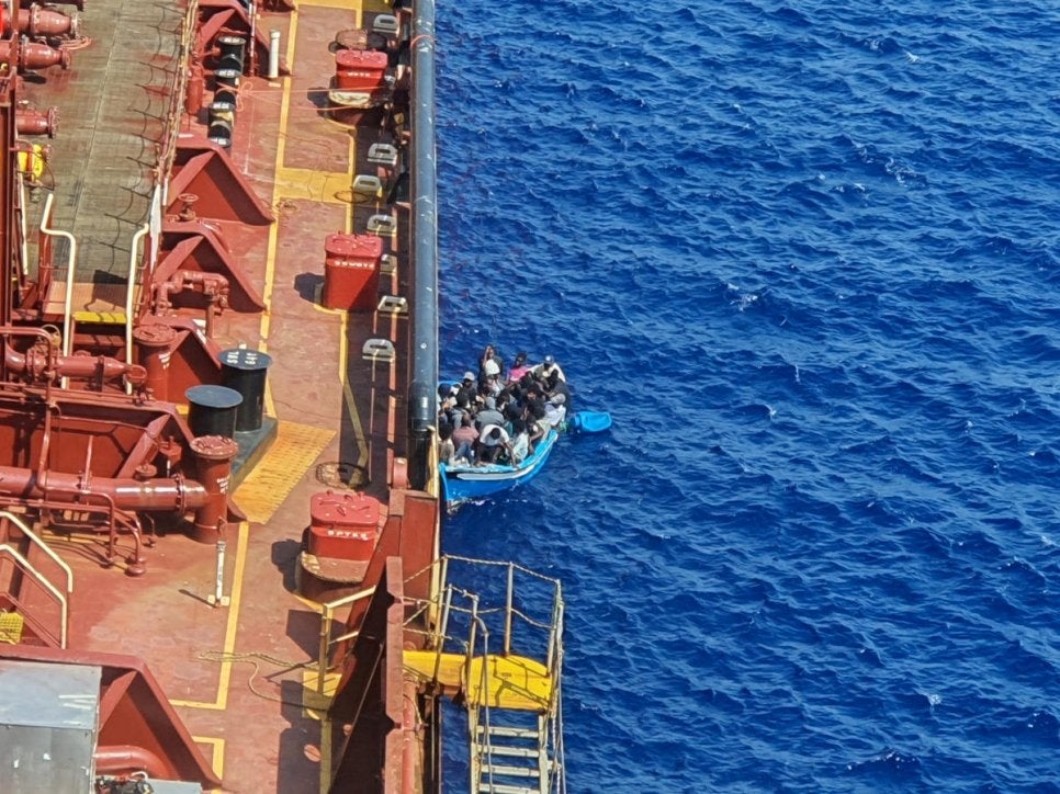 Migrants and refugees sit in a boat alongside the Maersk Etienne tanker off the coast of Malta, in this handout image provided 19 August, 2020.   