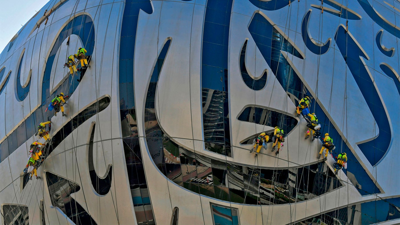 Workers clean the exterior of the Museum of the Future, currently under construction, in Dubai on November 19, 2020.