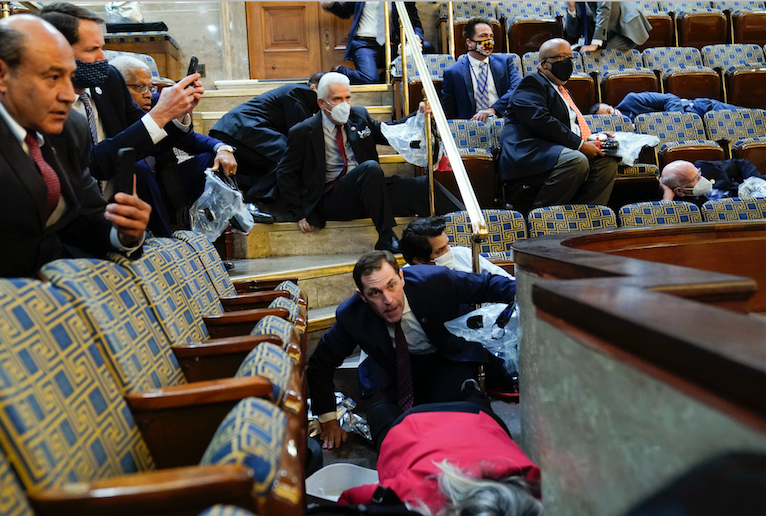 People shelter in the House gallery as protesters try to break into the House Chamber at the U.S. Capitol on Wednesday, Jan. 6, 2021, in Washington.