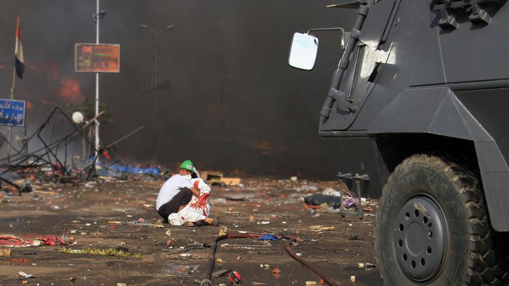 A volunteer tends to an injured demonstrator in front of a police armored personnel carrier (APC) in Rab’a Square in Cairo, Egypt on August 14, 2013