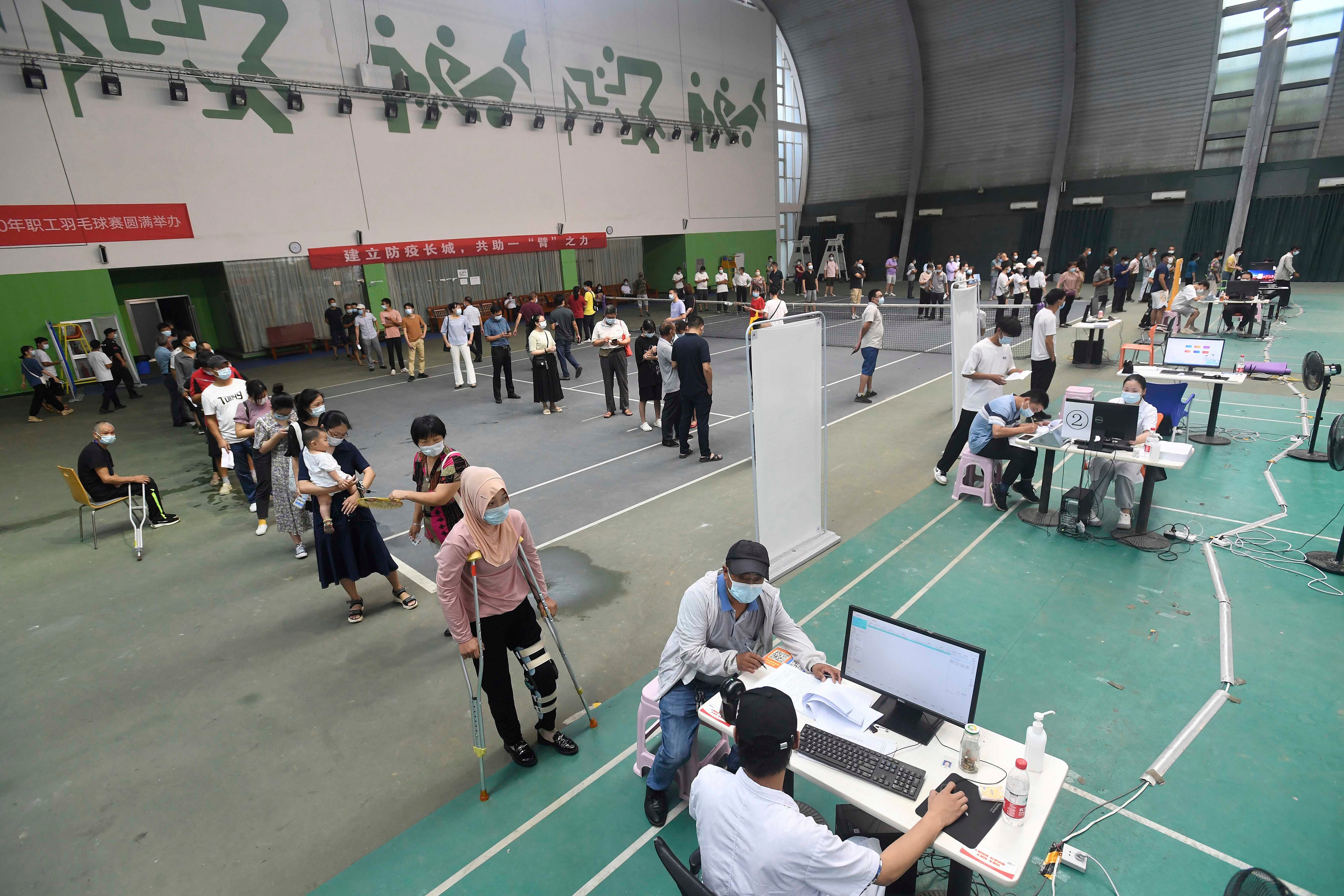 Migrant workers line up for the Covid-19 vaccine at a temporary inoculation site in Wuhan in central China's Hubei province, August 23, 2021. 