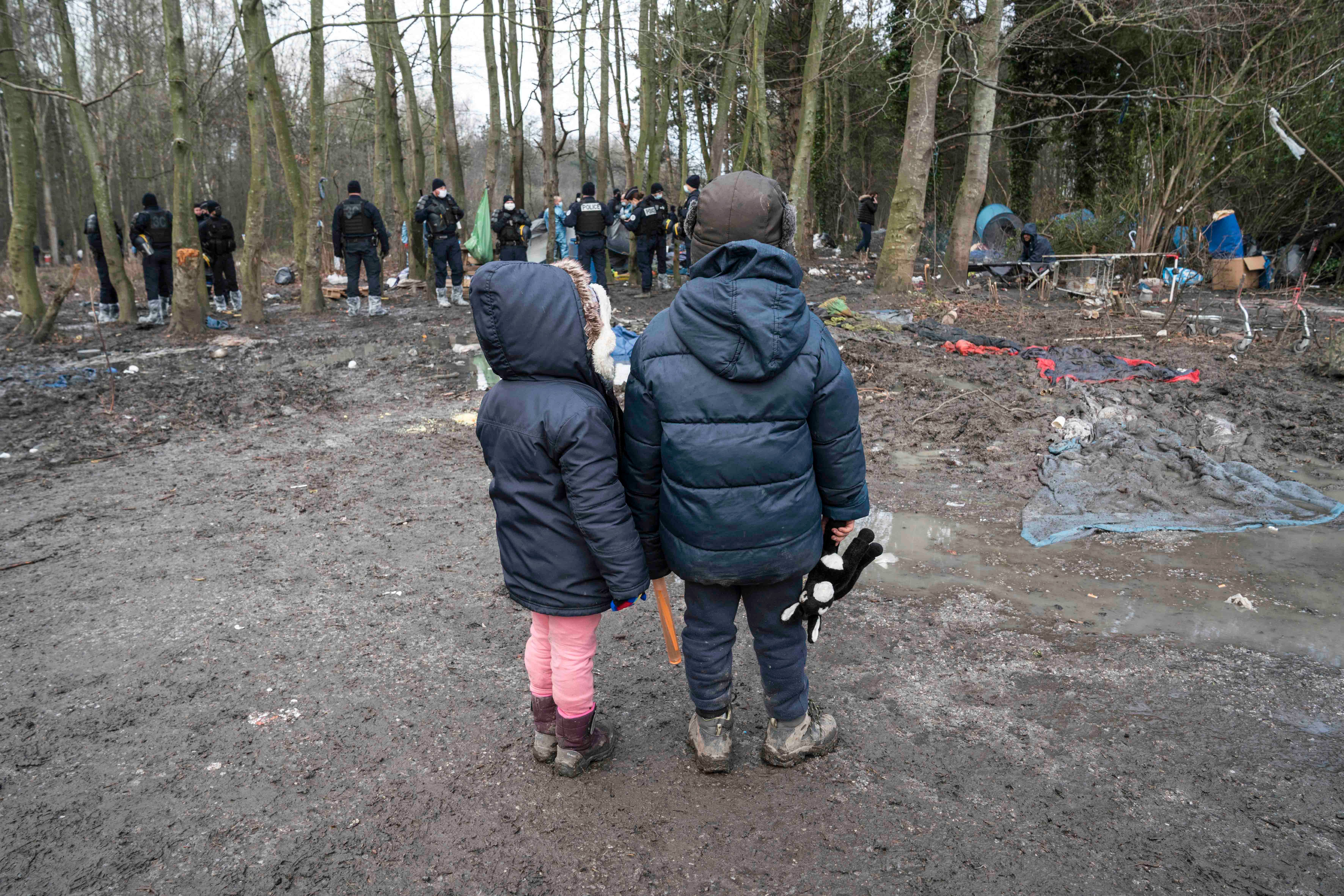 Deux enfants regardent la police saisir leur tente durant l’expulsion d’un campement à Grande-Synthe, dans le nord de la France, le 21 janvier 2021.