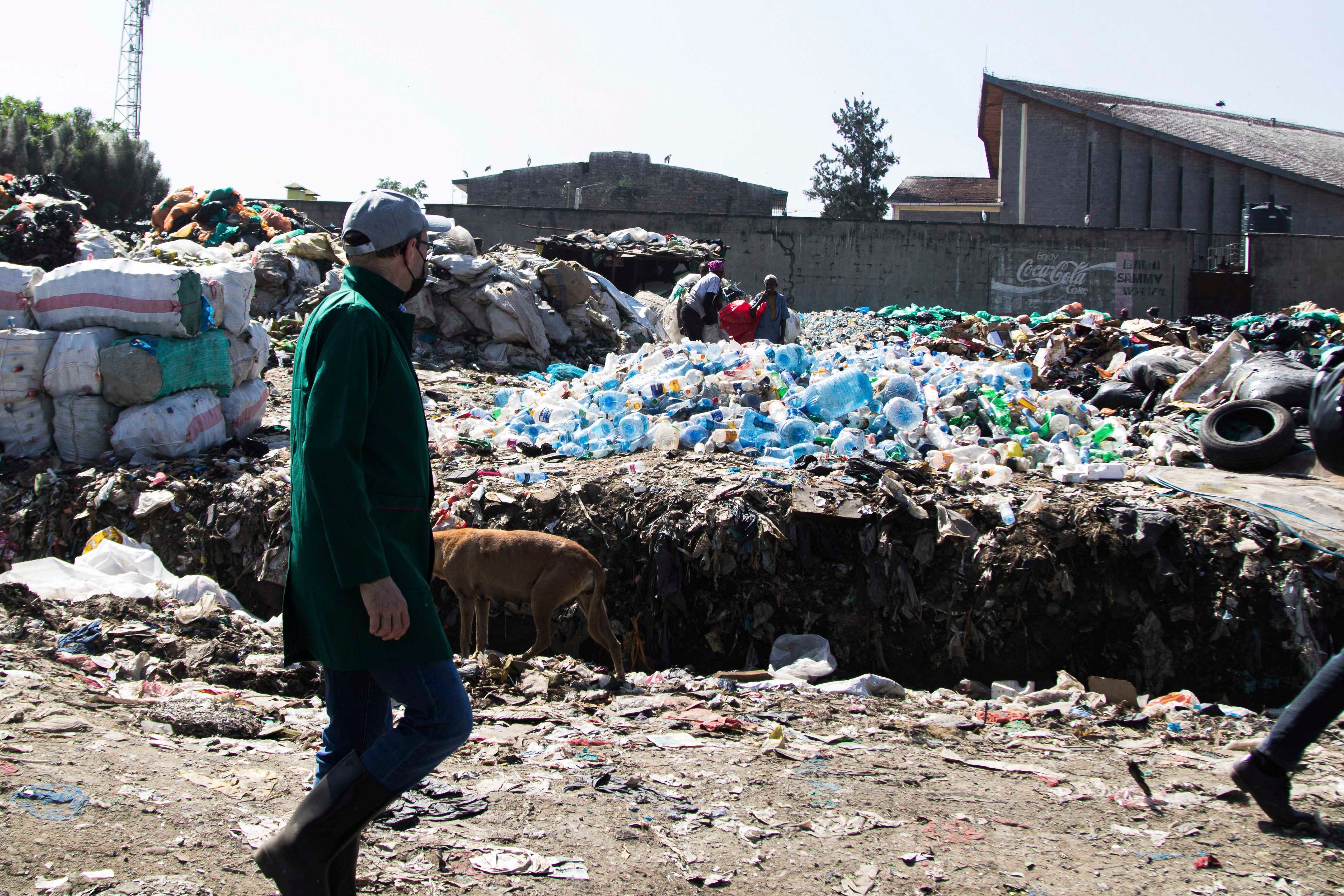 A man walks by a mound of plastic waste