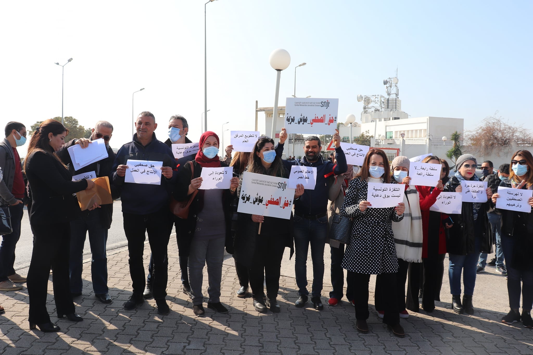 A group of people holding protest signs in Arabic