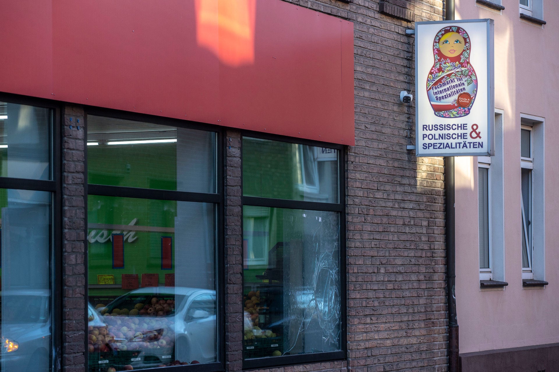 A smashed window pane and smeared white paint are seen on a Russian-Polish supermarket