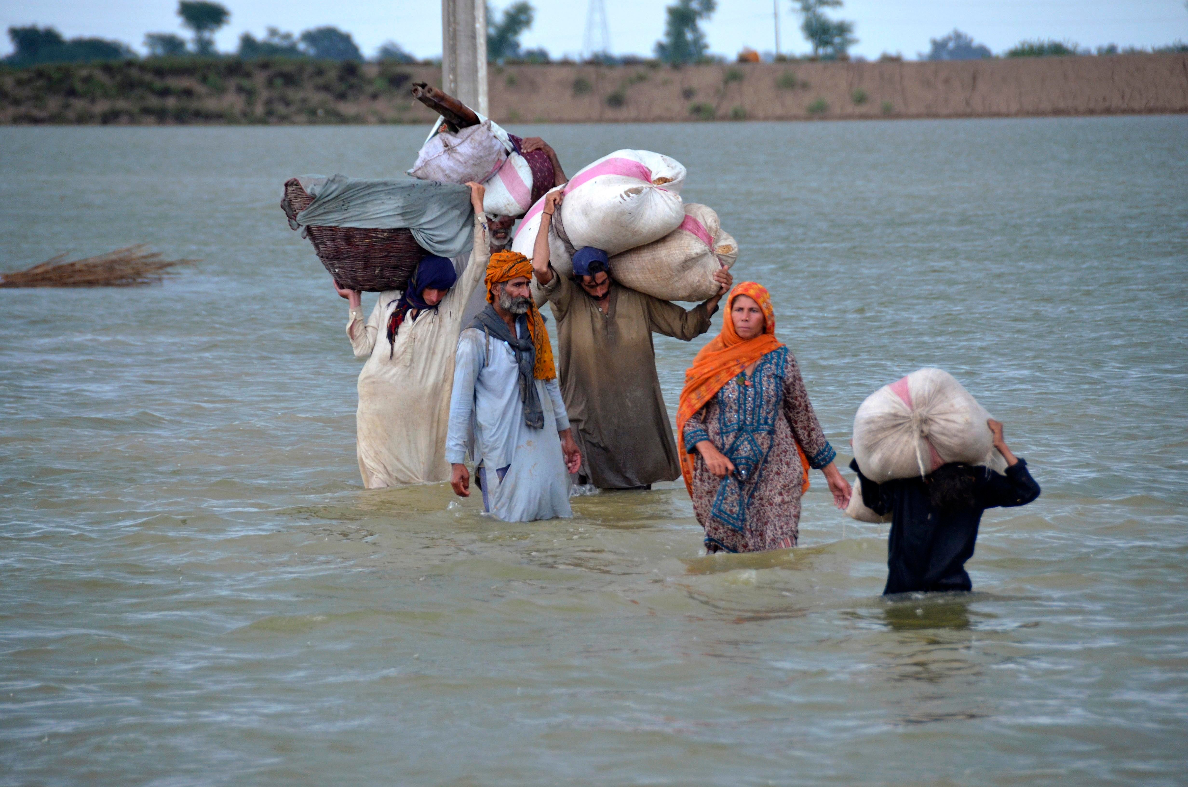 A displaced family wades through a flooded area in Jaffarabad