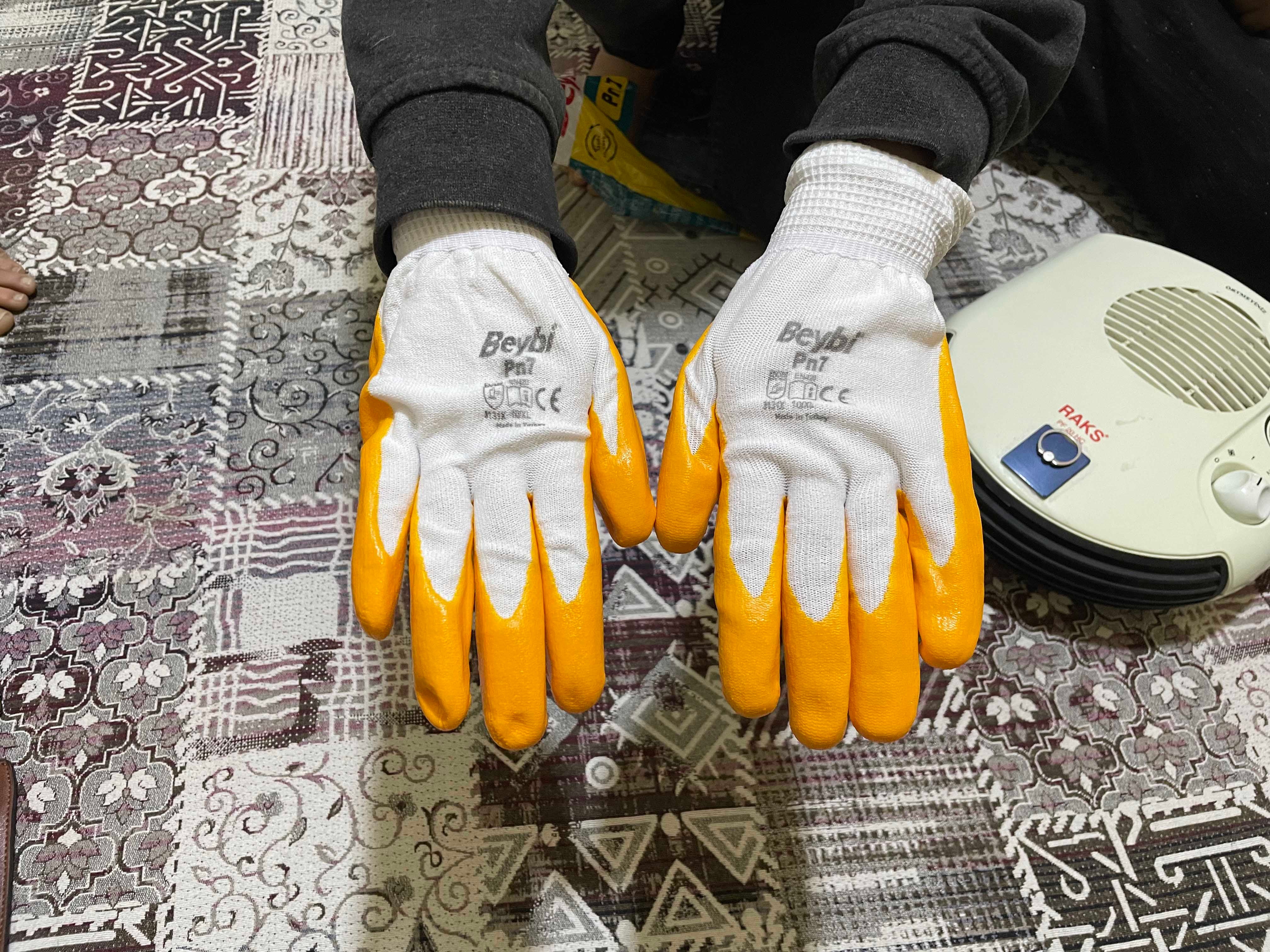A person displays a pair of gloves