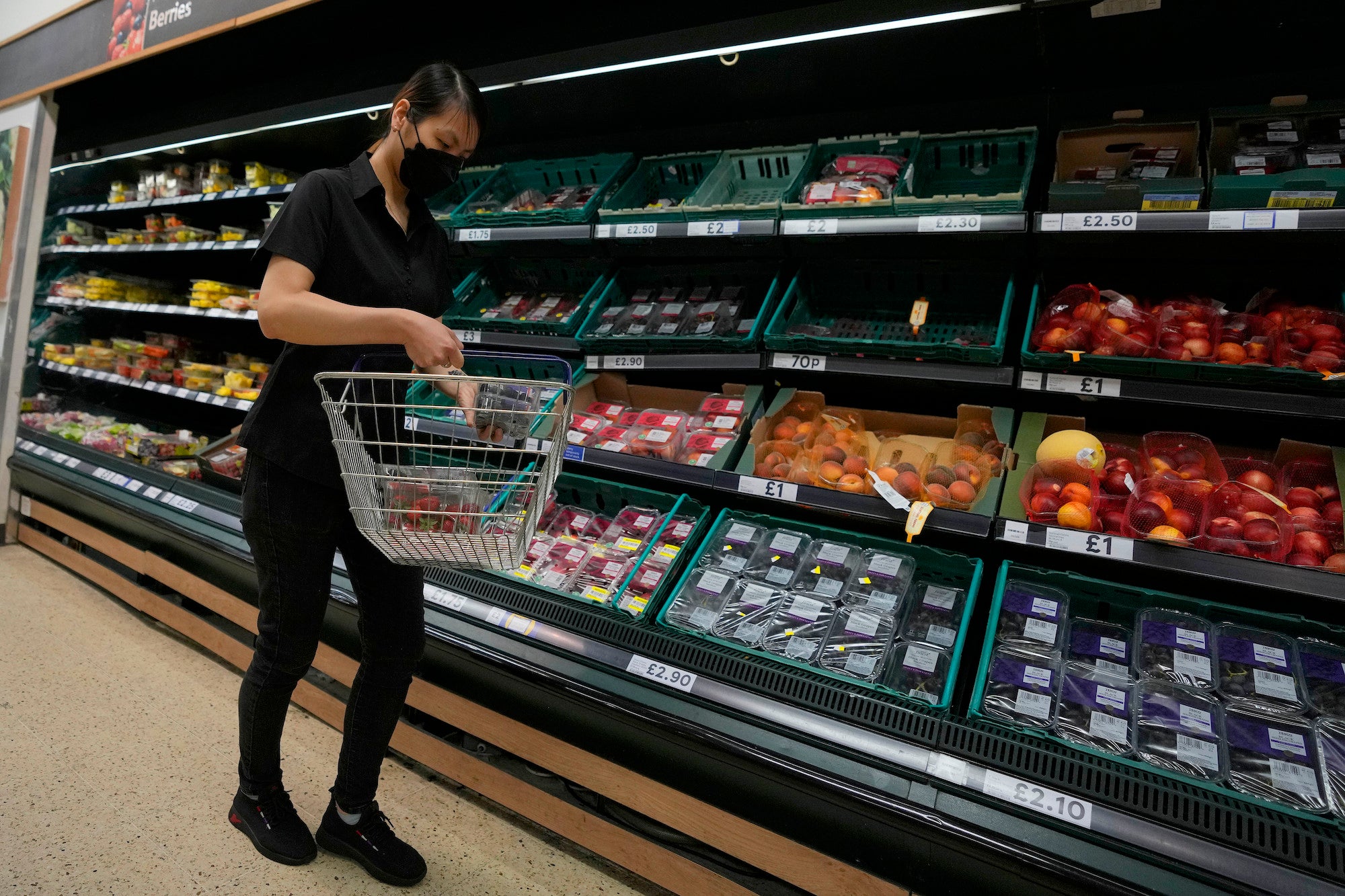 A shopper puts fruit in her basket in a supermarket in London.