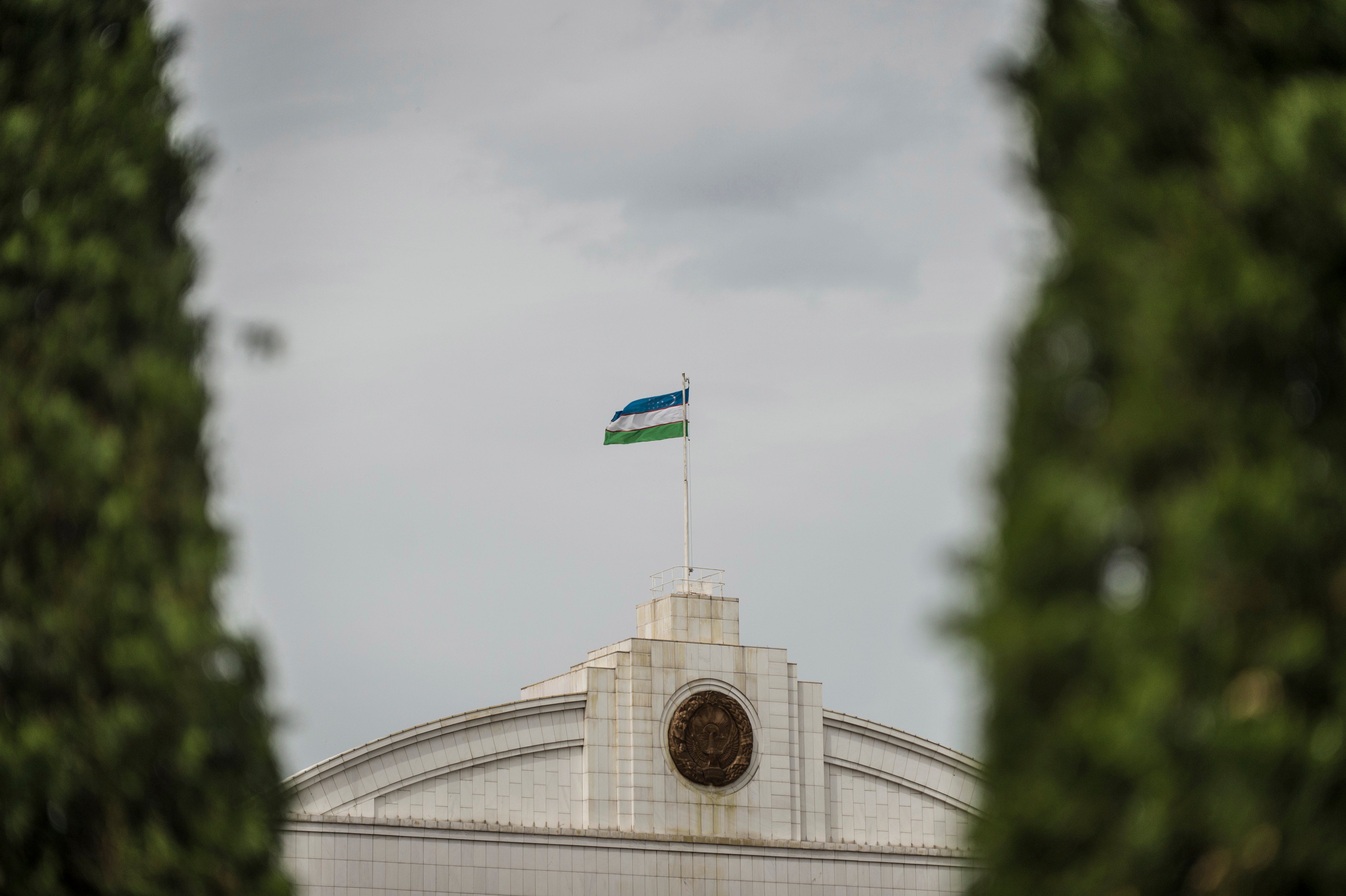 The Uzbekistan flag flies at the top of a government building