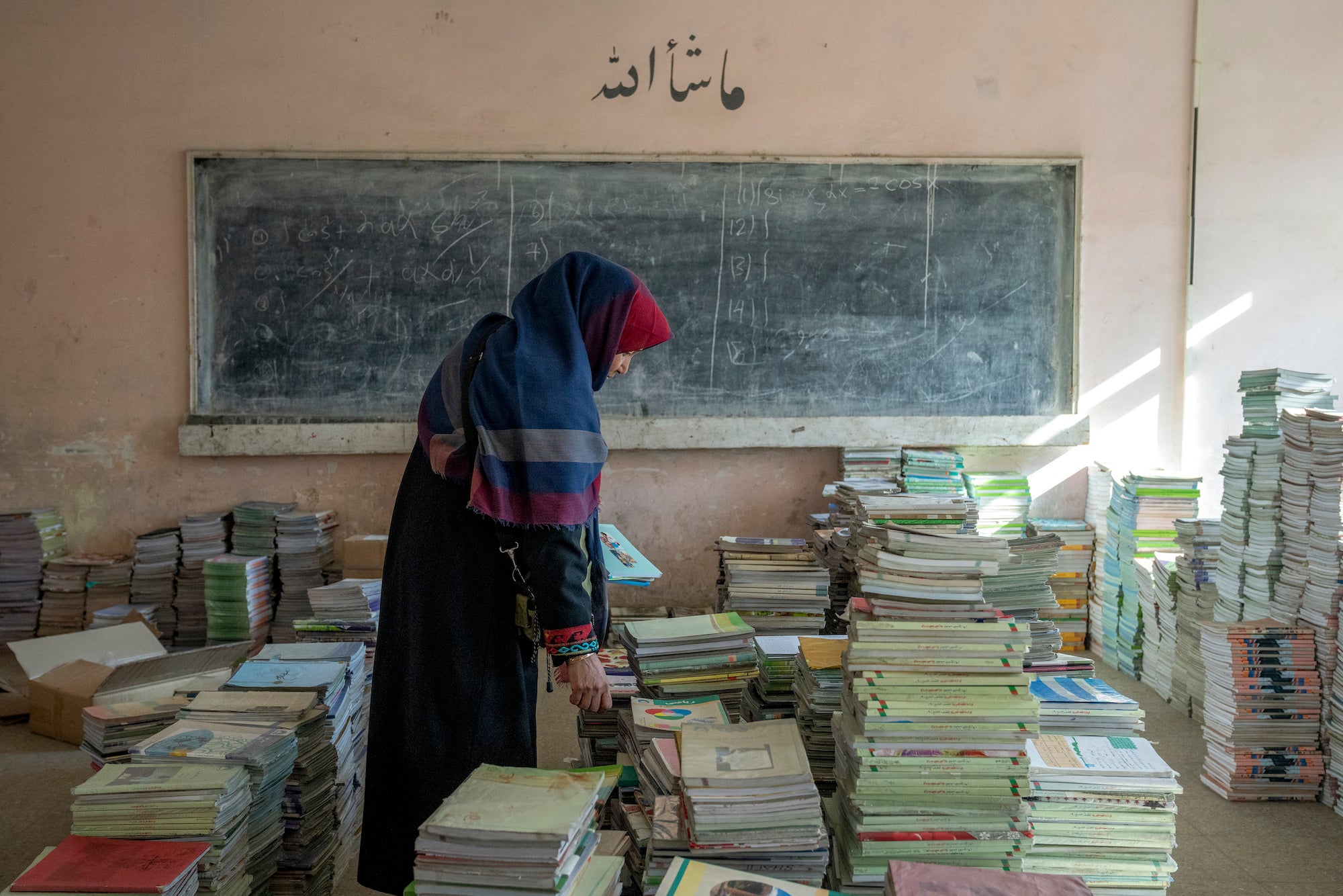 An Afghan teacher collects books in a school in Kabul, Afghanistan.