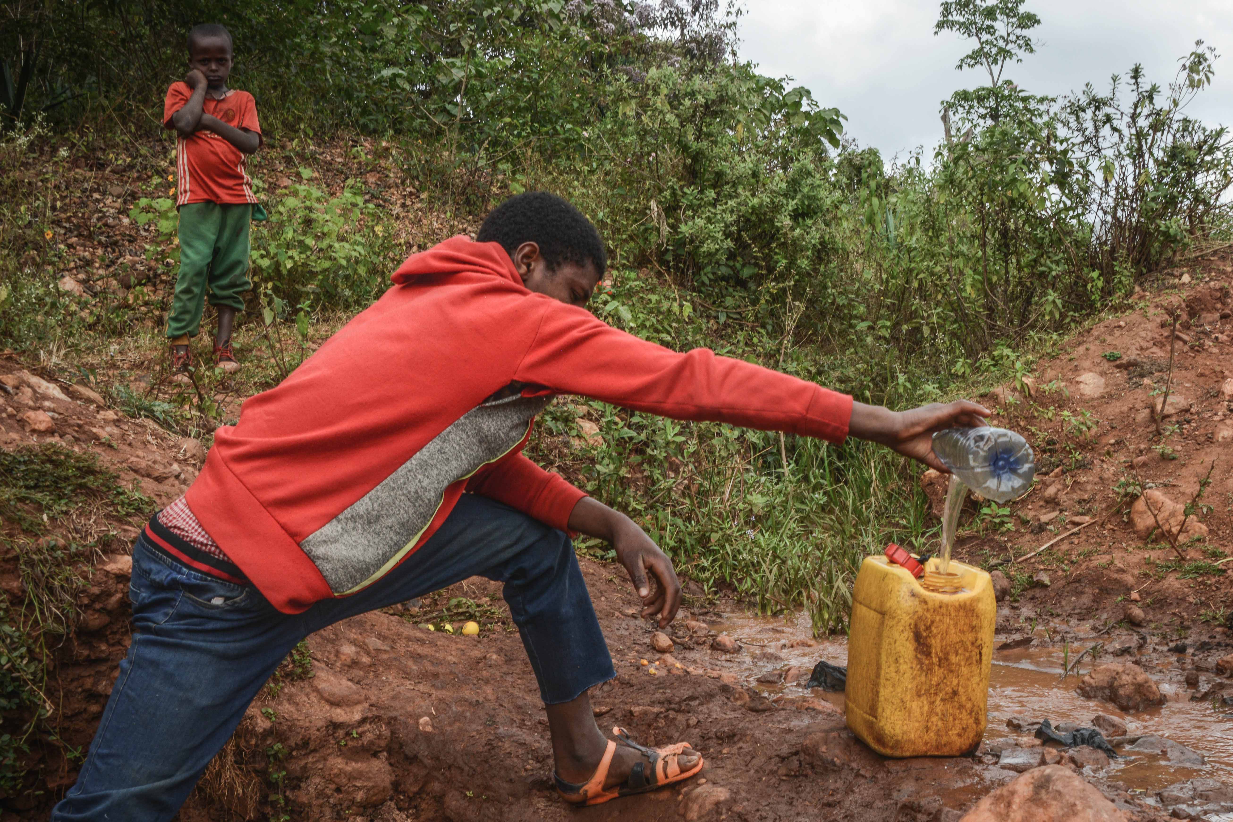 A 16-year-old boy collects water from a spring near Lega Dembi gold mine in the Oromia region of Ethiopia. @2020 Tom Gardner 