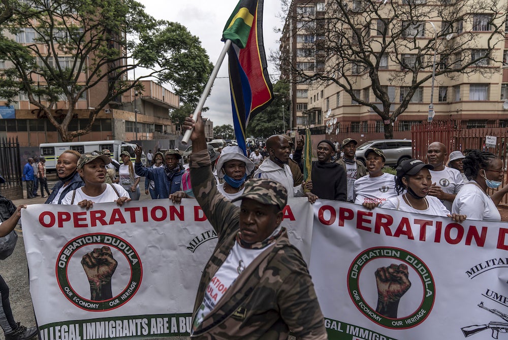 A man holds up a South African flag as members of "Operation Dudula" march down a street in the Hillbrow neighborhood to deliver memoranda to several businesses in the area, Johannesburg, South Africa, February 19, 2022. 