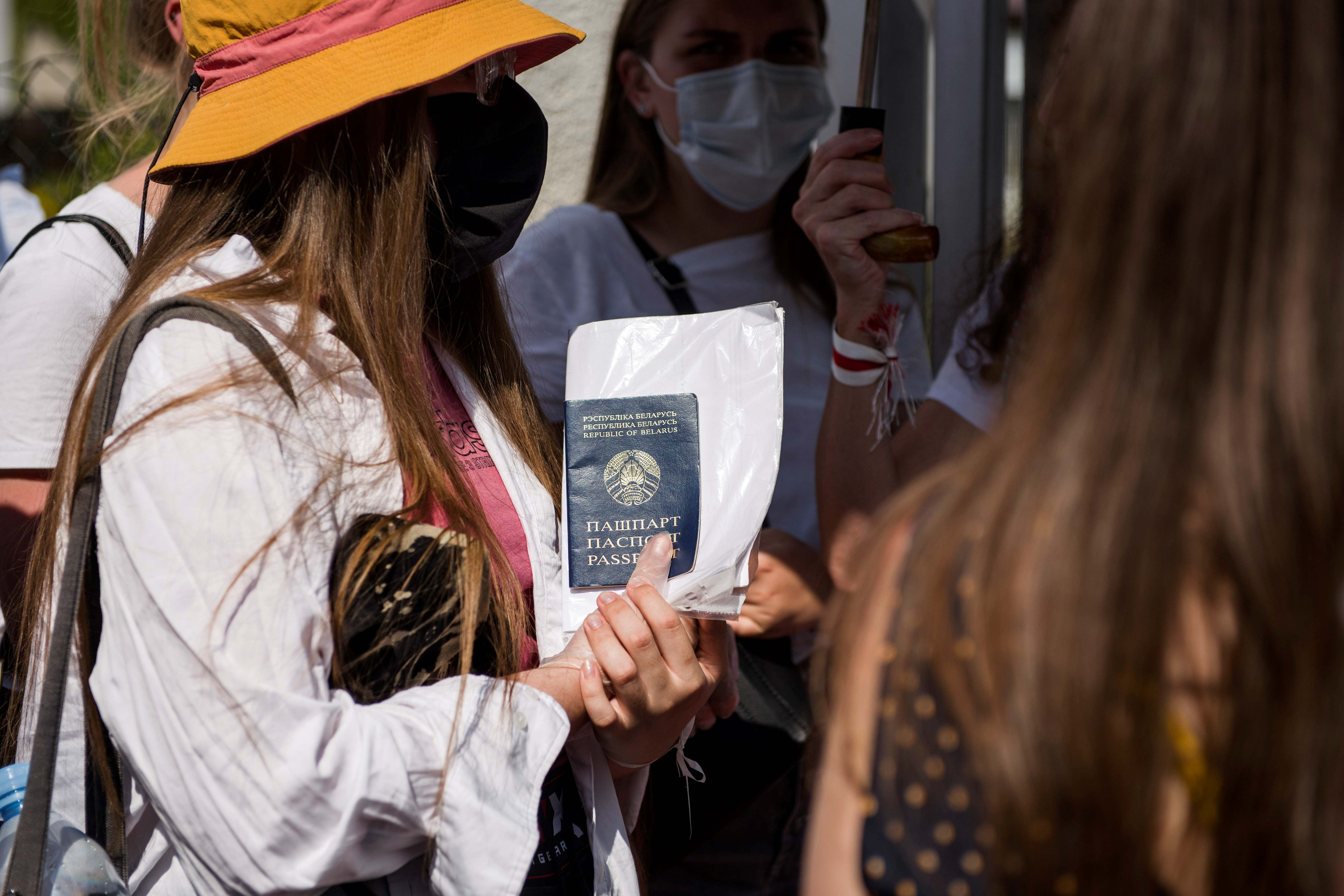 A Belarusian woman holds her passport outside the Belarusian Embassy in Warsaw, Poland, August 9, 2020. 
