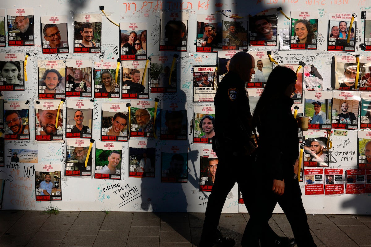 People pass by portraits of Israeli hostages from Israel held in Gaza since the October 7 attacks in Tel Aviv, December 17, 2023. 