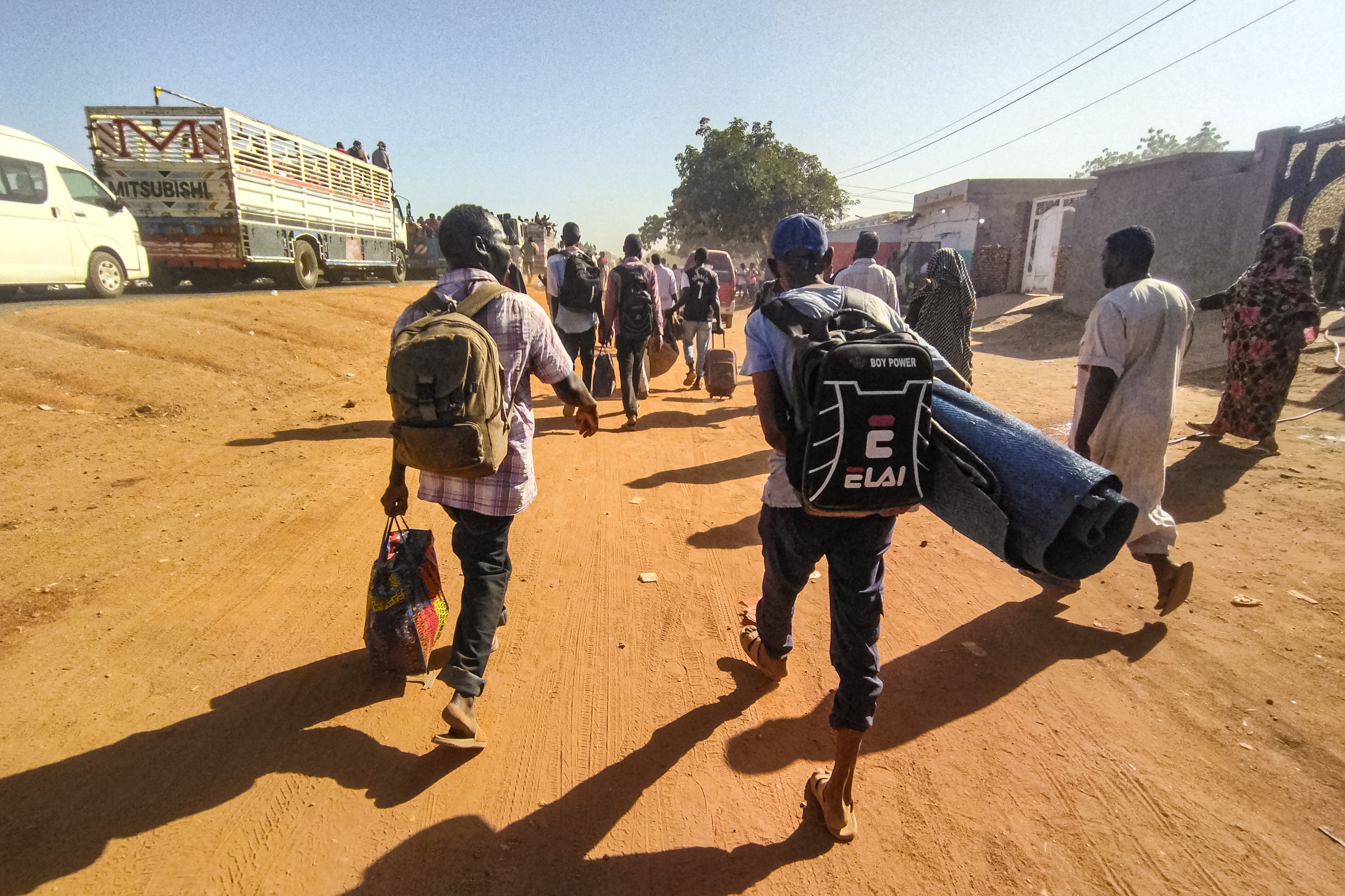 People displaced by conflict walk with their belongings in Wad Madani, the capital of al-Jazirah state, Sudan, December 16, 2023.