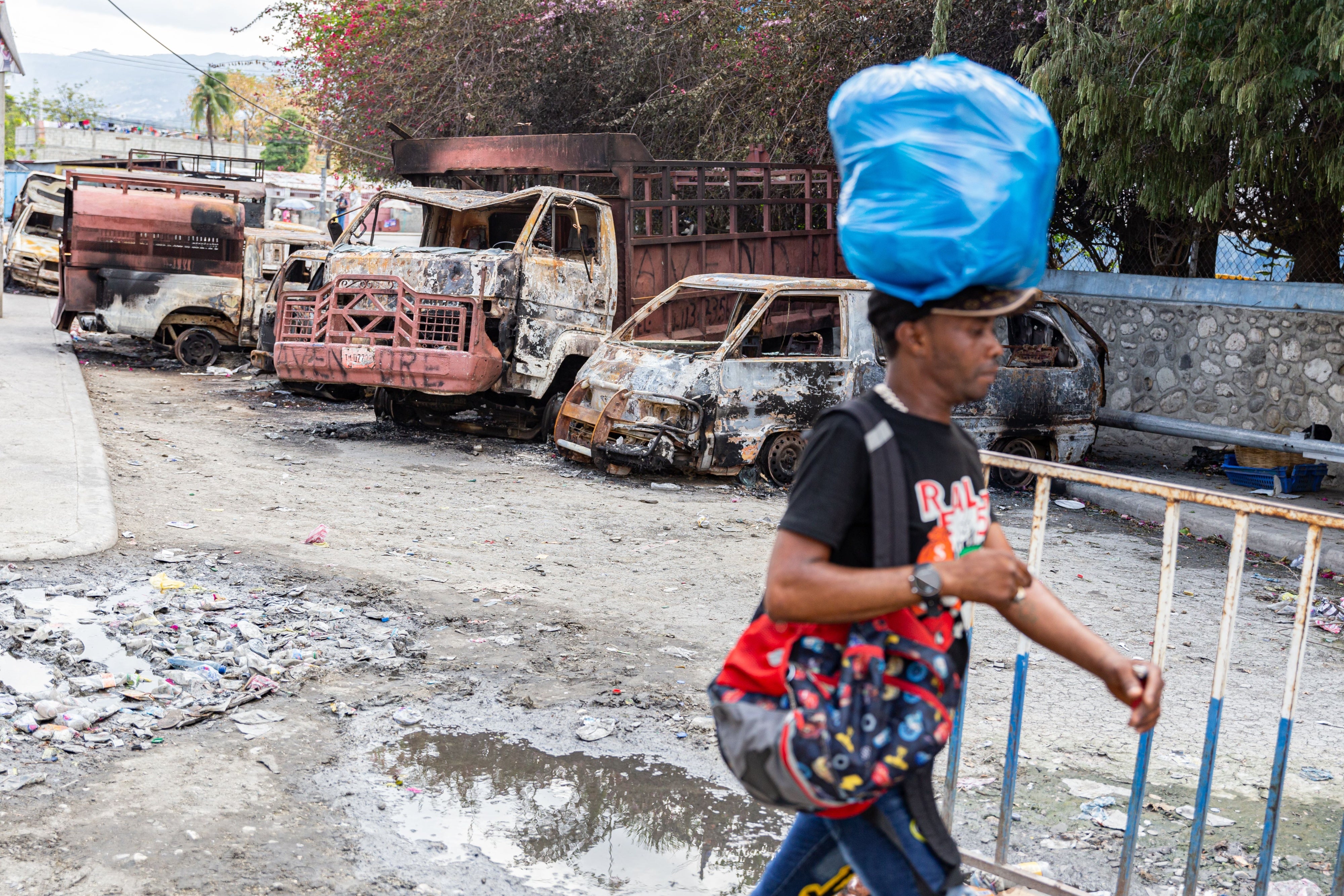 A man walks past several torched cars