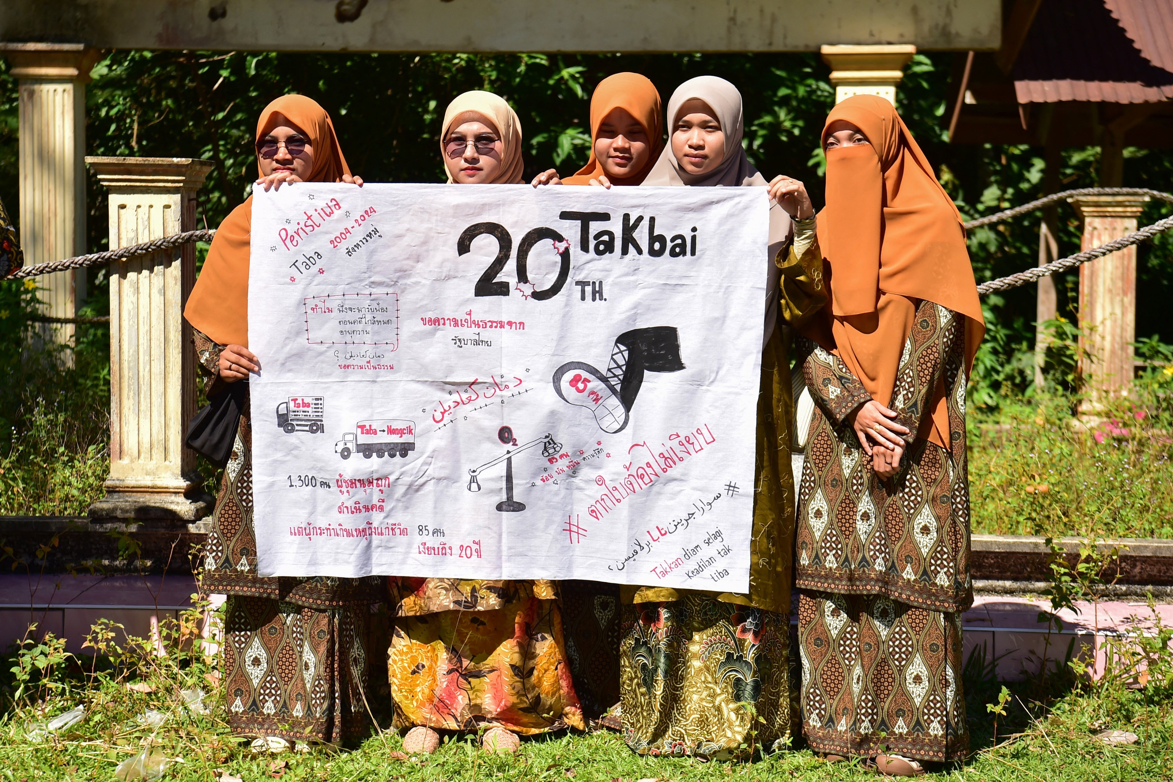 Des femmes musulmanes tenaient une affiche marquant le 20ème anniversaire du massacre survenu le 25 octobre 2004 à Tak Bai (province de Narathiwat) dans le sud de la Thaïlande, le 25 octobre 2024 ; elles s’étaient réunies près d’une fosse commune où de nombreuses victimes étaient enterrées.