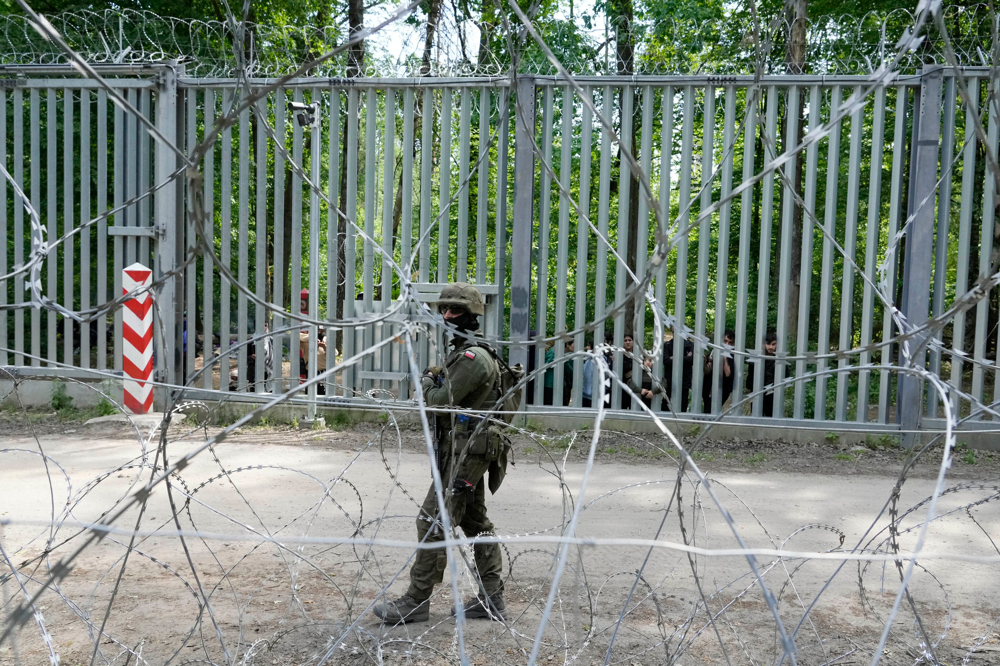A Polish soldier patrols the metal barrier border with Belarus, in Bialowieza Forest, with migrants stranded on the Belarusian side, May 29, 2024.