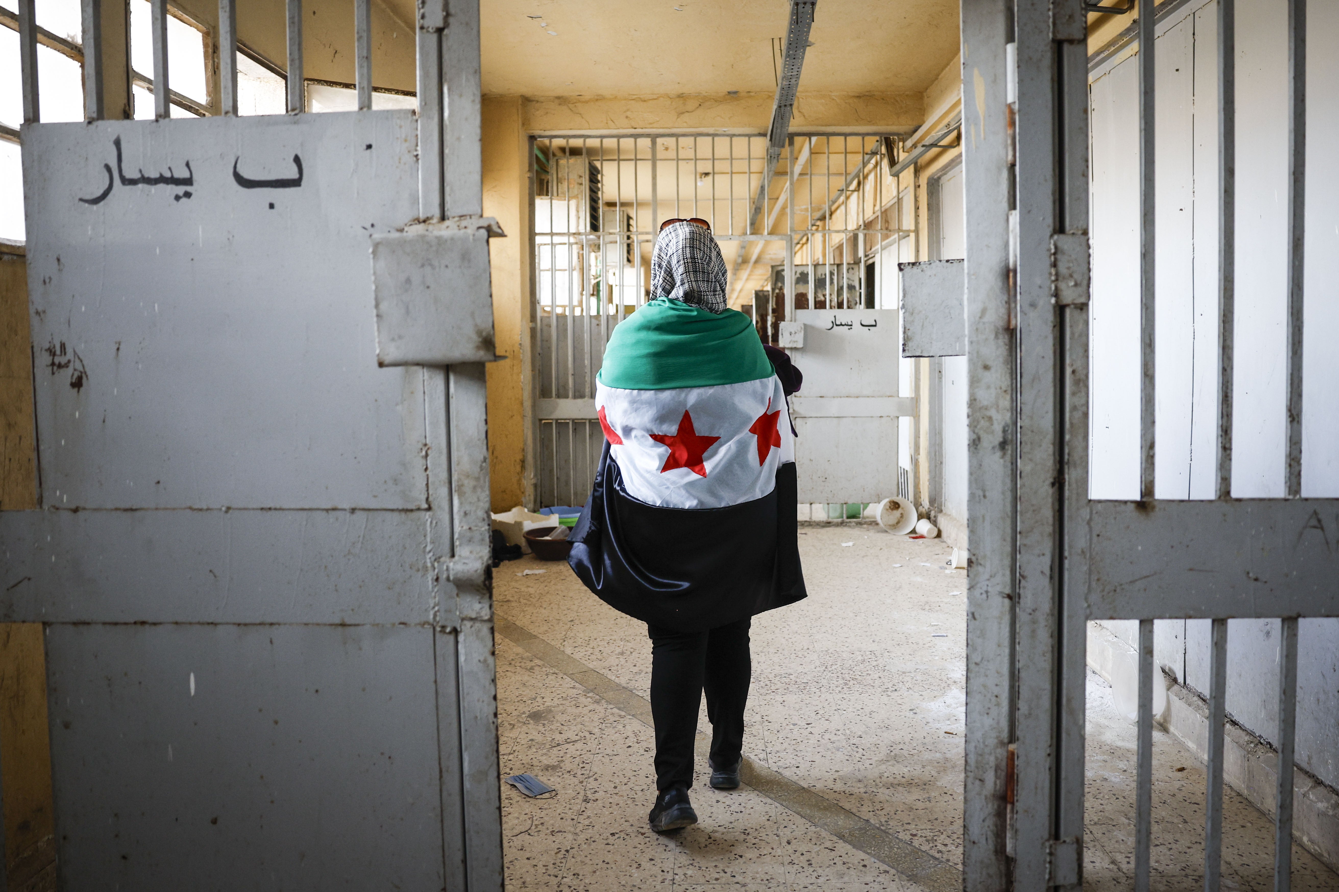 Une femme enveloppée dans un drapeau de l'opposition syrienne marchait dans un couloir de la prison de Sednaya, près de Damas, en Syrie, le 12 décembre 2024. 
