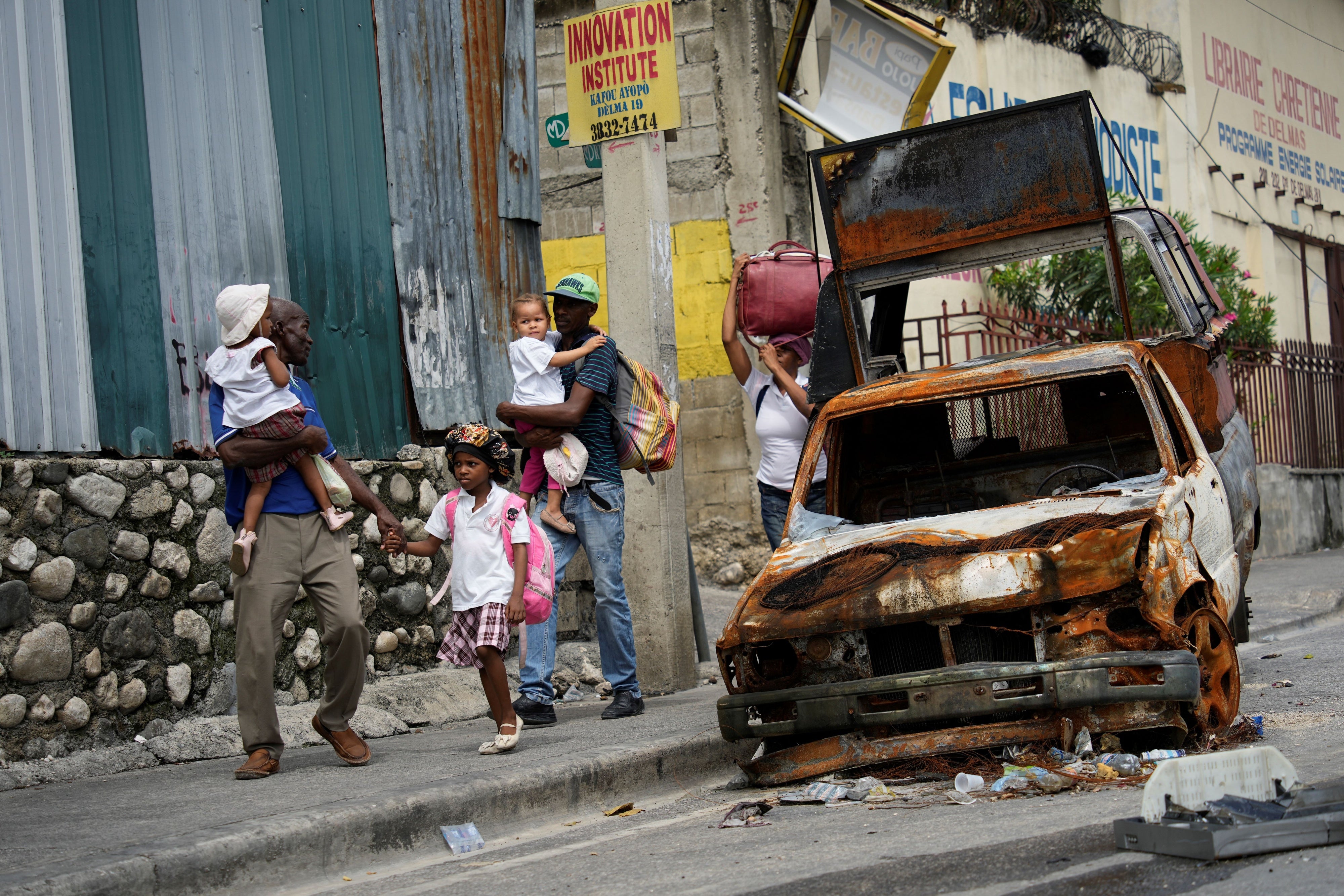 Des habitants du quartier de Delmas 22 à Port-au-Prince, en Haïti, marchaient près d’une voiture incendiée en quittant cette zone touchée par une vague de violence criminelle, le 2 mai 2024.