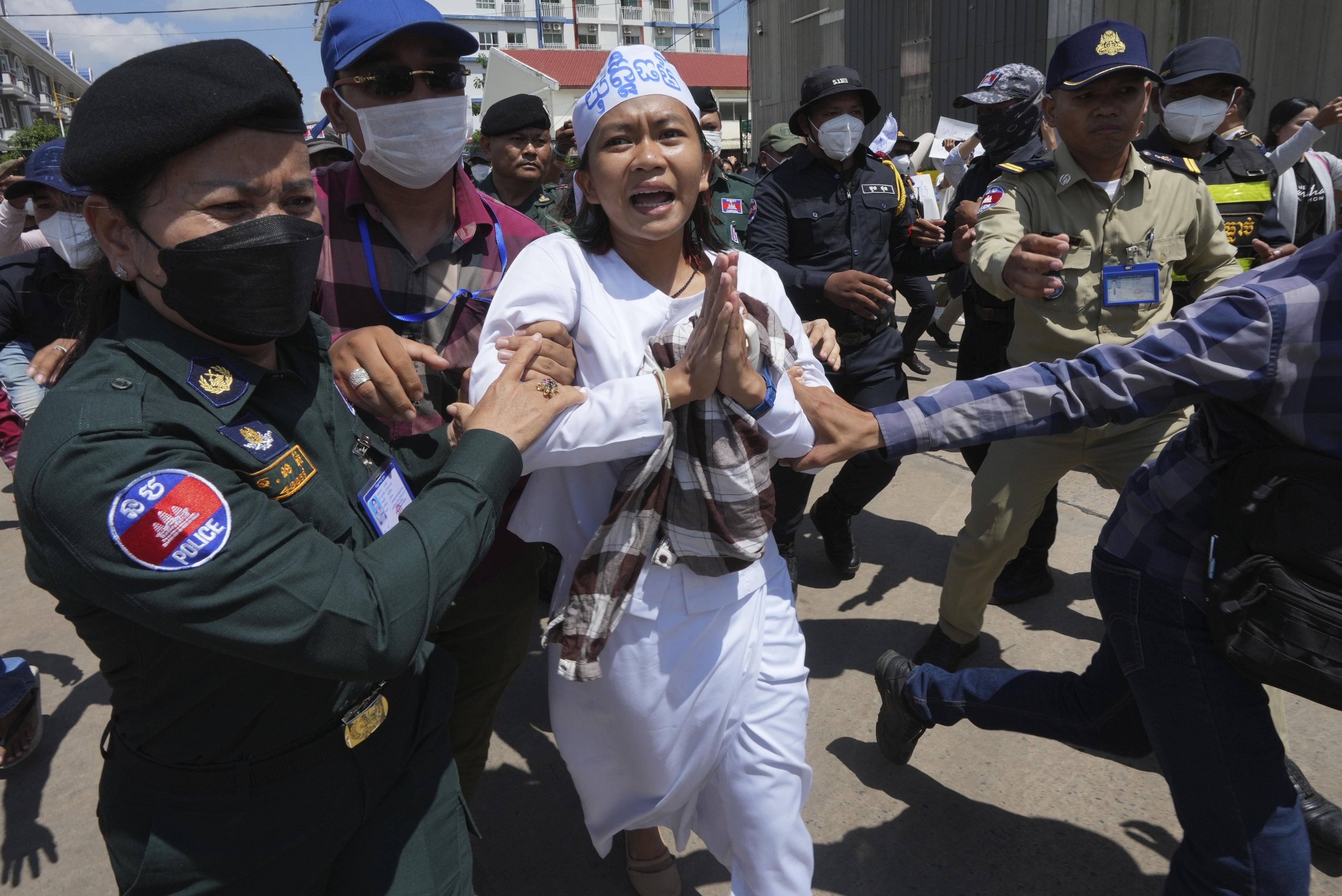 Environmental activist Phuon Keoraksmey is escorted by police officers