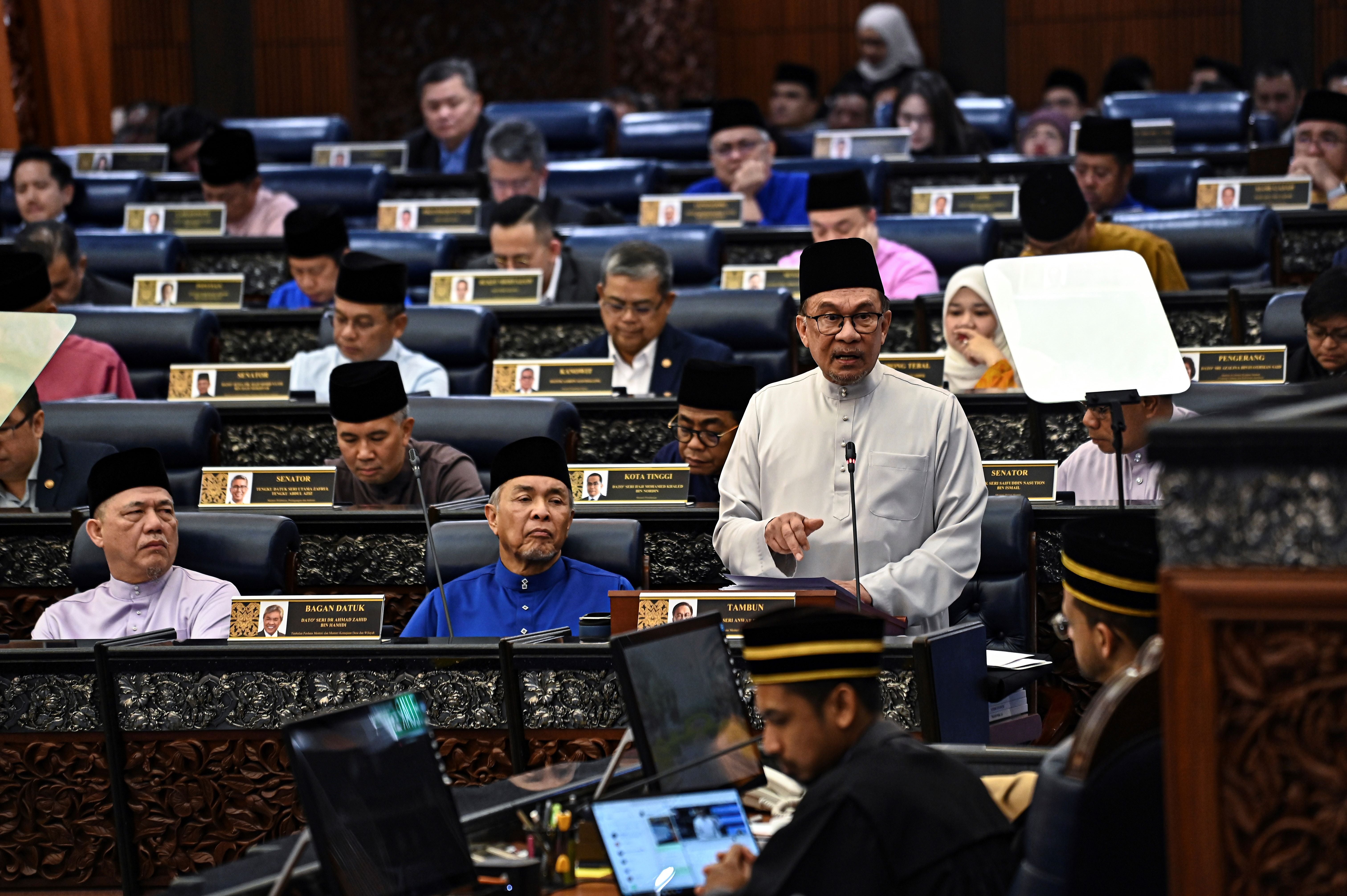Perdana Menteri Malaysia Anwar Ibrahim, yang juga Menteri Kewangan, membentangkan teks belanjawan 2025 di parlimen, Malaysia, 18 Oktober, 2024.