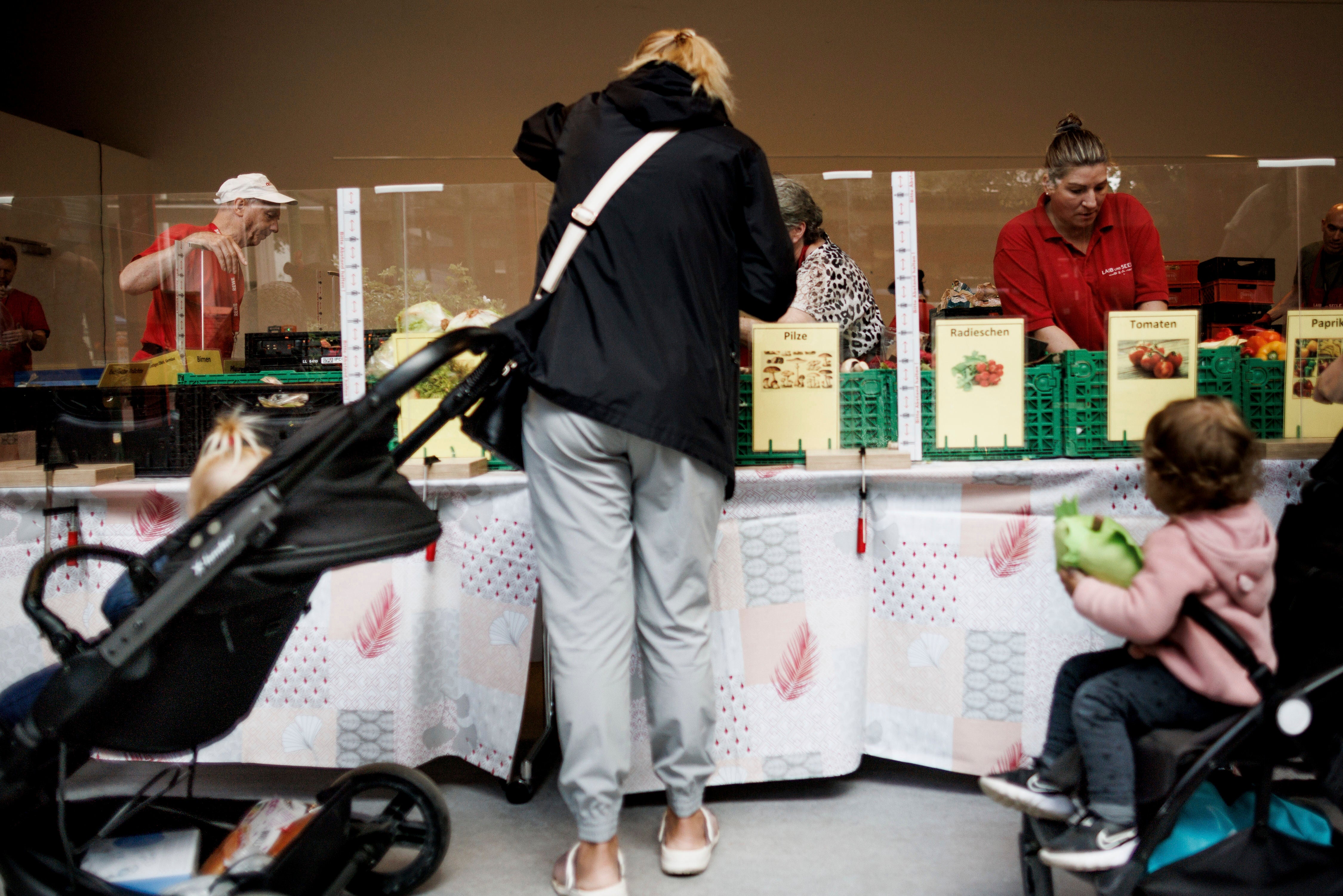 A woman at a food distribution center next to two strollers
