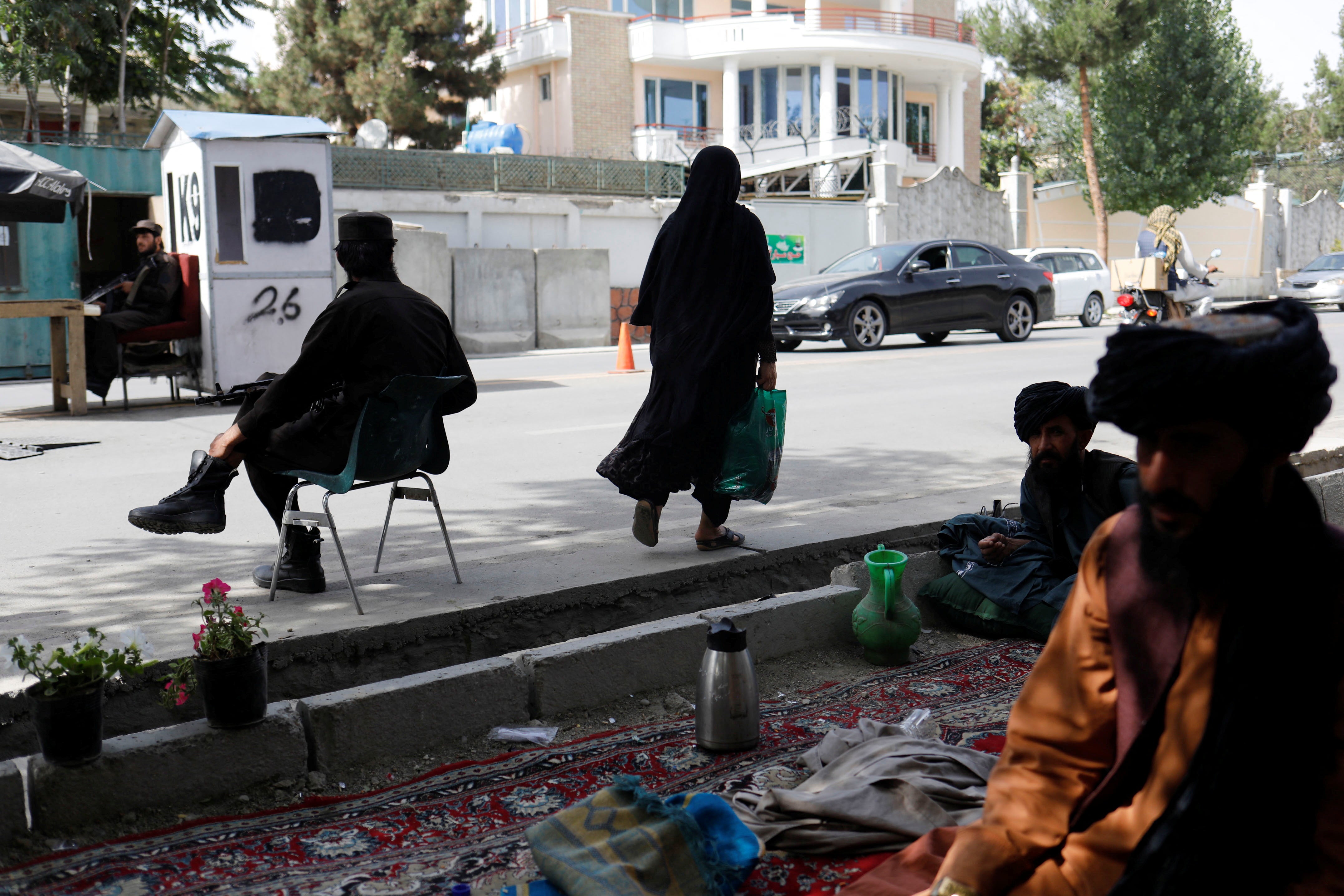 An Afghan woman walks among Taliban soldiers at a checkpoint in Kabul, Afghanistan, July 6, 2023. 