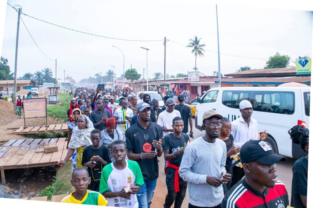 Une foule marche dans une rue.