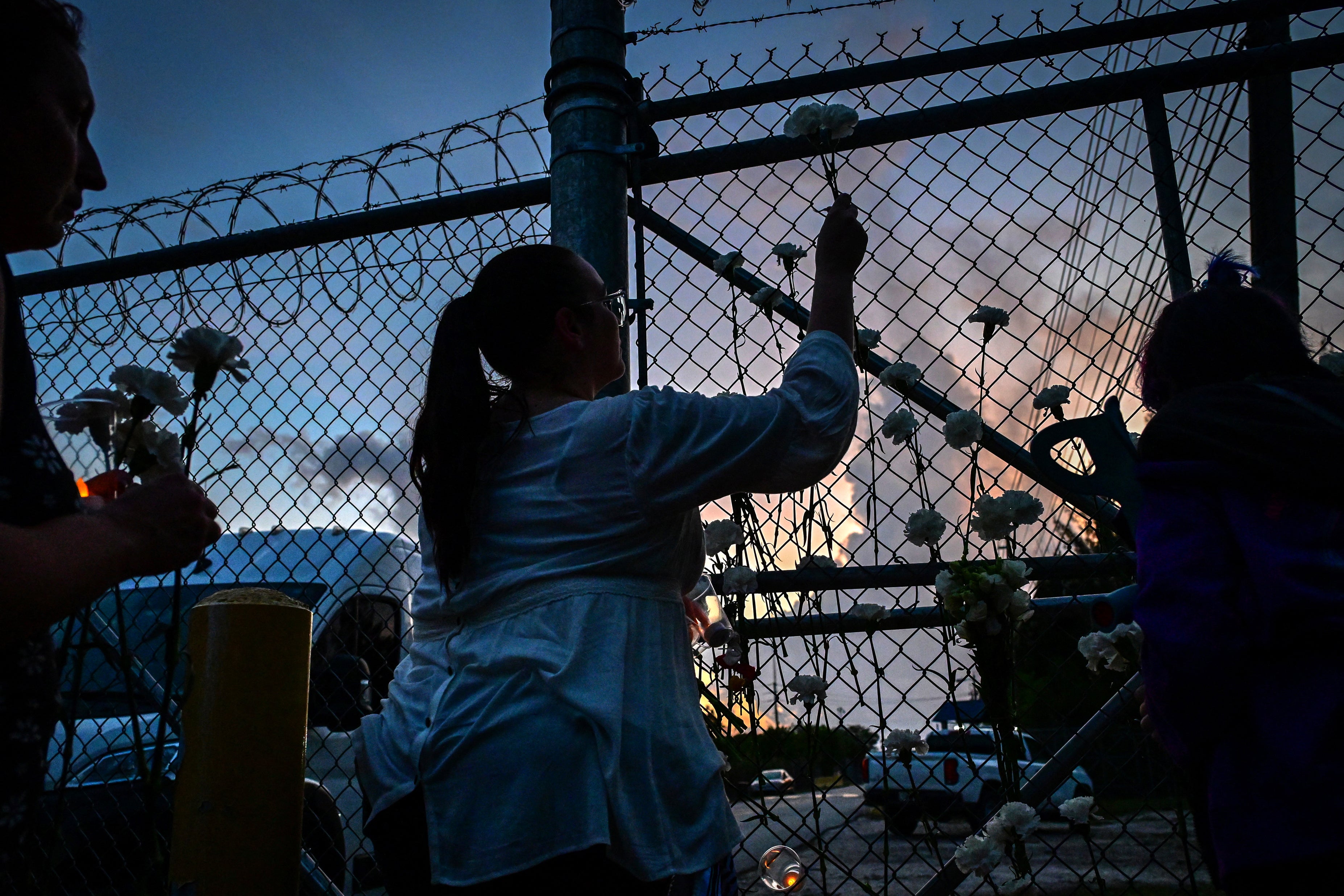 People place flowers on the fence of the Krome Detention Center during a vigil protesting US Immigration and Customs Enforcement custody and mass deportations in Miami, Florida, May 24, 2025.
