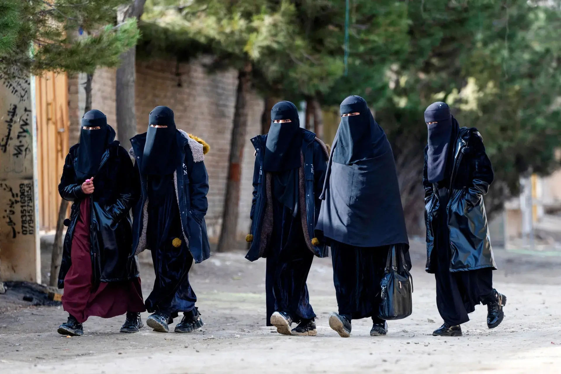 Afghan niqab-clad women walk along a street on the outskirts of Kabul.