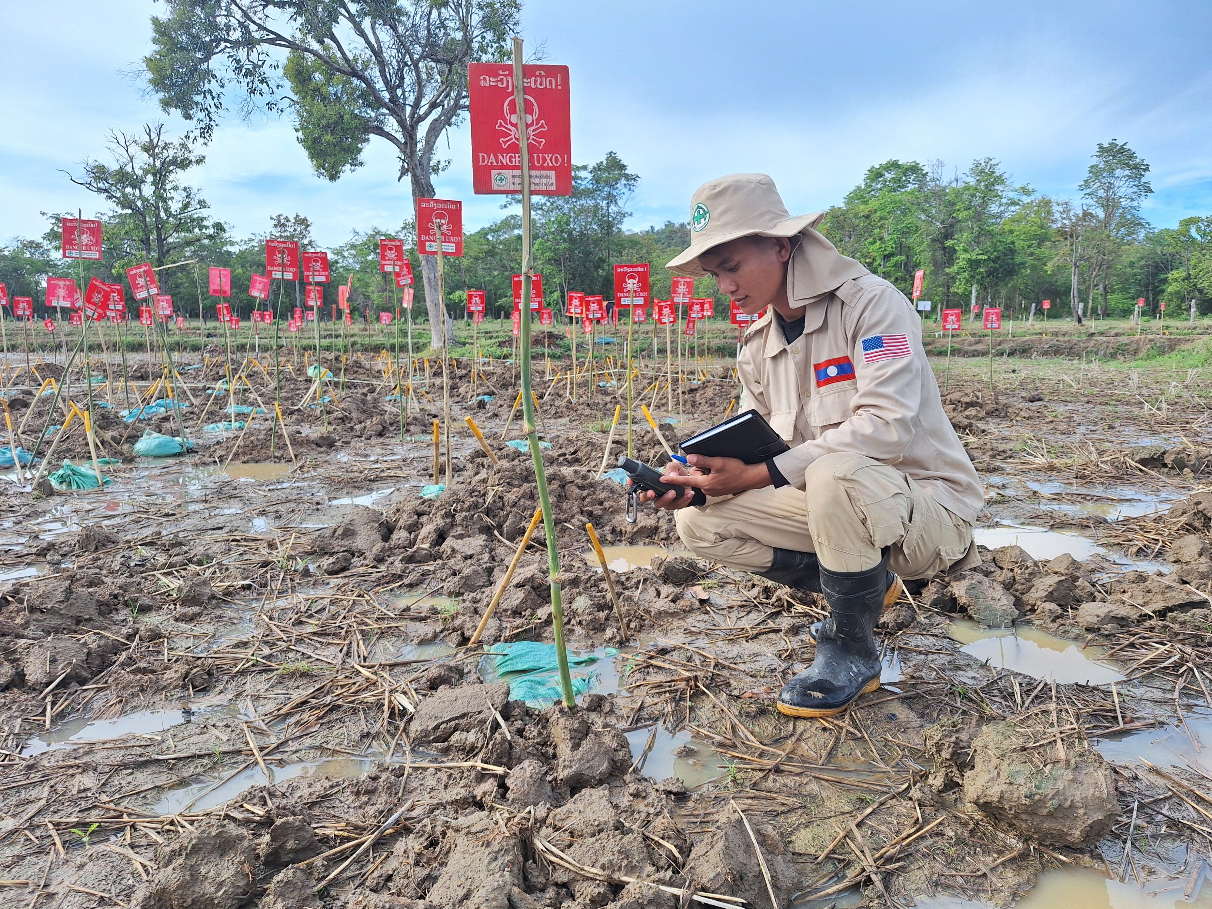 In Paksong district of Saravane province, Laos, a clearance technician from Norwegian People’s Aid uses a GPS device to record the coordinates of cluster munition remnants in a rice field where 178 BLU-26 submunitions were found. 