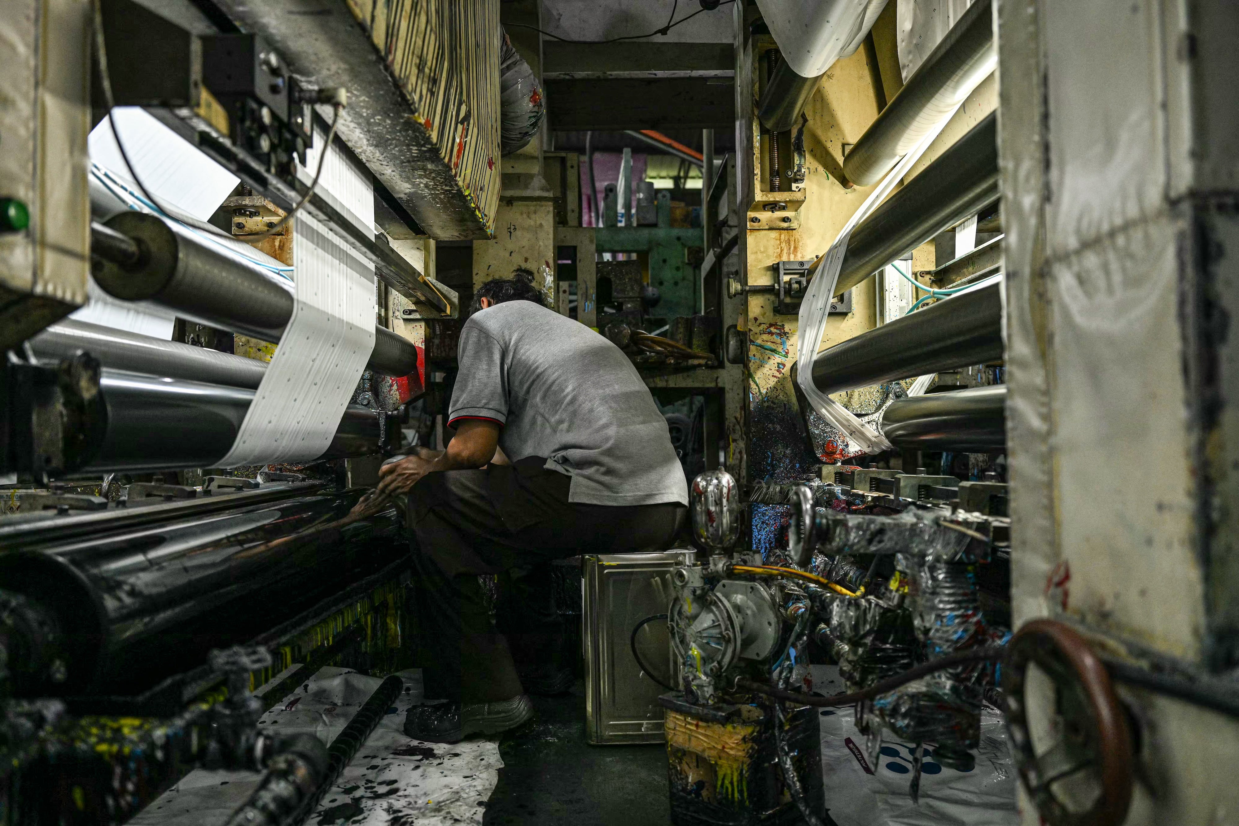 A worker inspects a machine processing color for plastic products at a factory in Malaysia, October 9, 2024.