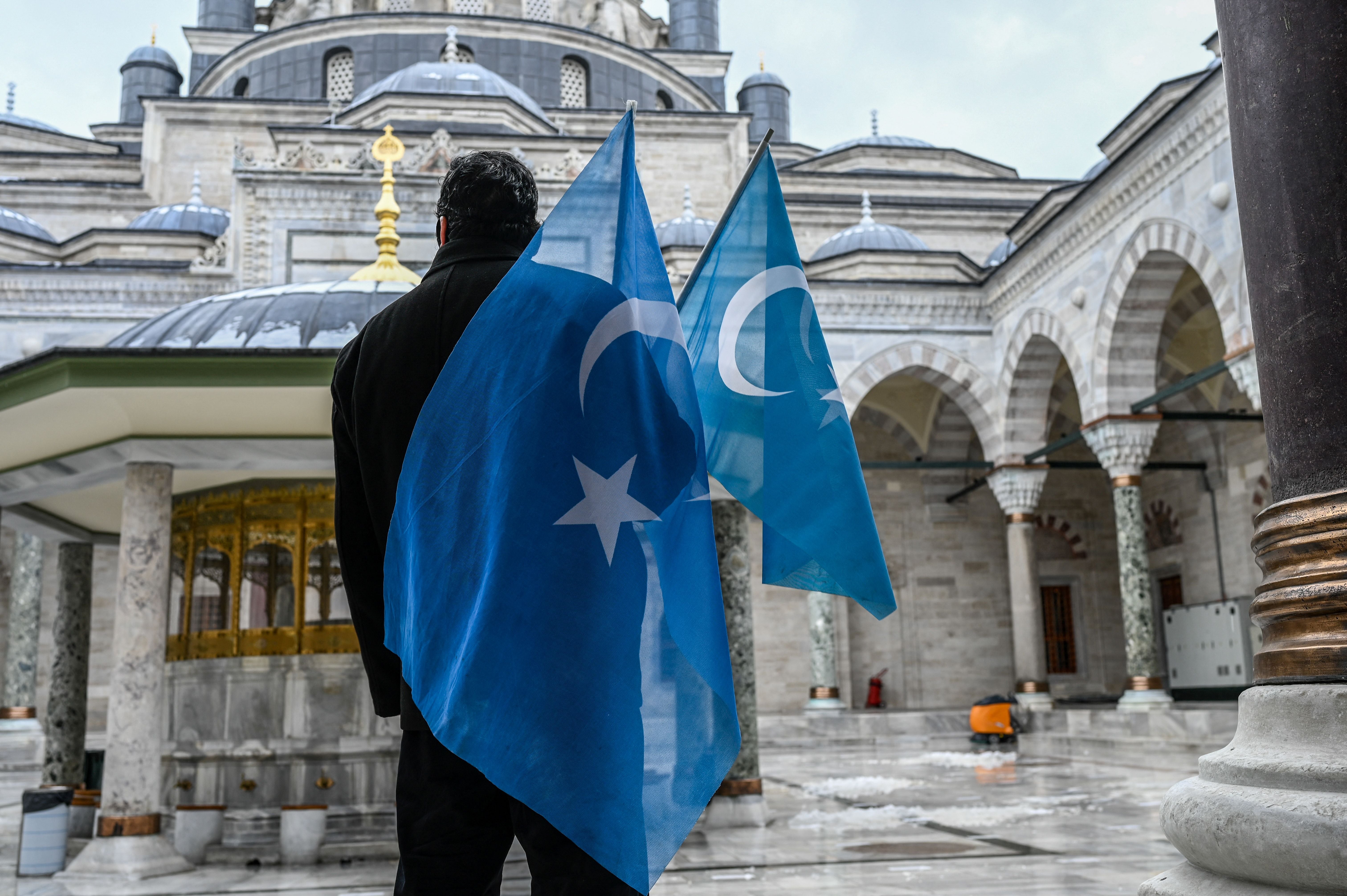 A man holding flags outside of a mosque