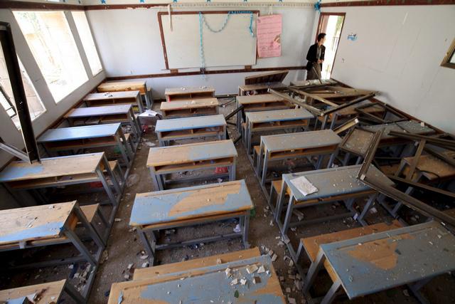 A man looks at a damaged classroom in a school after an air strike in Sanaa April 28, 2015. 