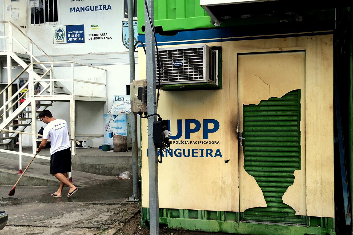 A military police officer cleans the area around the Pacifying Police Unit (UPP) at the Mangueira favela on January 14, 2016. The UPP is made of metal shipping containers. © 2016 César Muñoz Acebes/Human Rights Watch