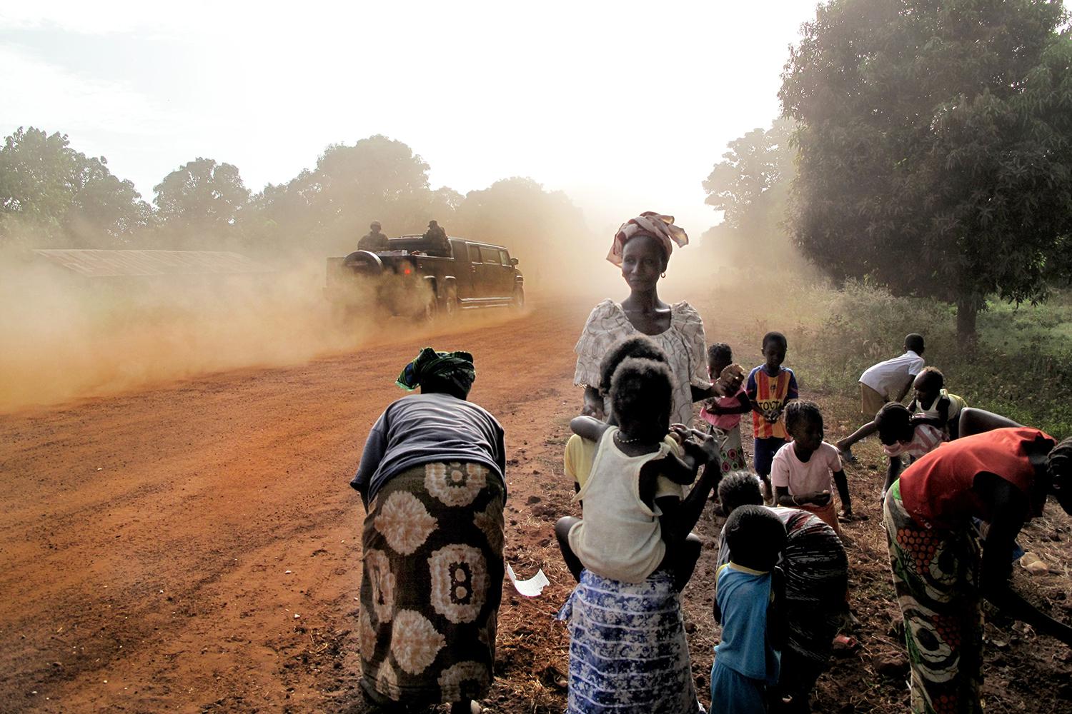 Gambia's President Jammeh's Hummer passes a group of women and children on January 25, 2014 in the Gambian village of Killin. 