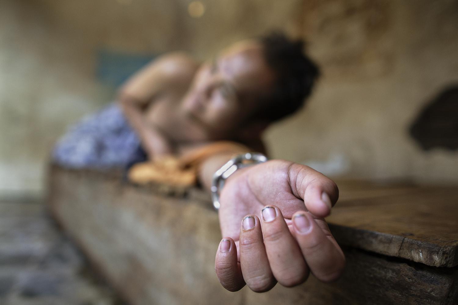 A man with a psychosocial disability lies chained at the wrist on a platform bed at the Bina Lestari healing center in Brebes, Central Java. All residents of the healing center are chained. © 2015 Andrea Star Reese for Human Rights Watch 