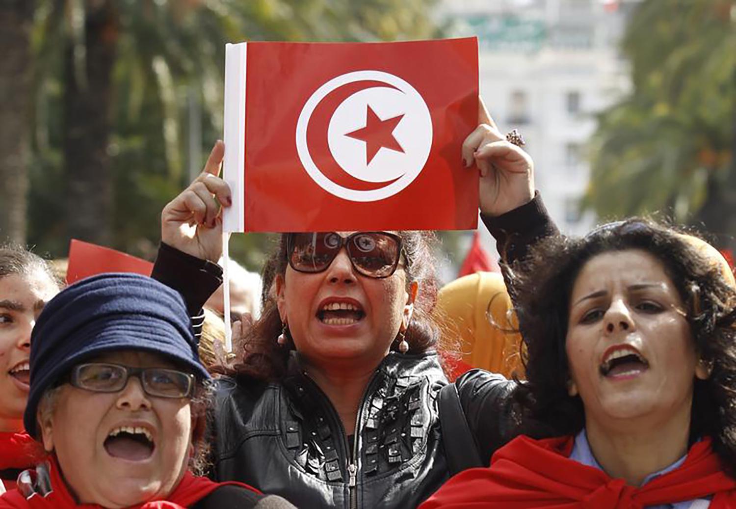 A Tunisian woman holds up a flag during a march to celebrate International Women's Day in Tunis March 8, 2014. © 2014 Reuters
