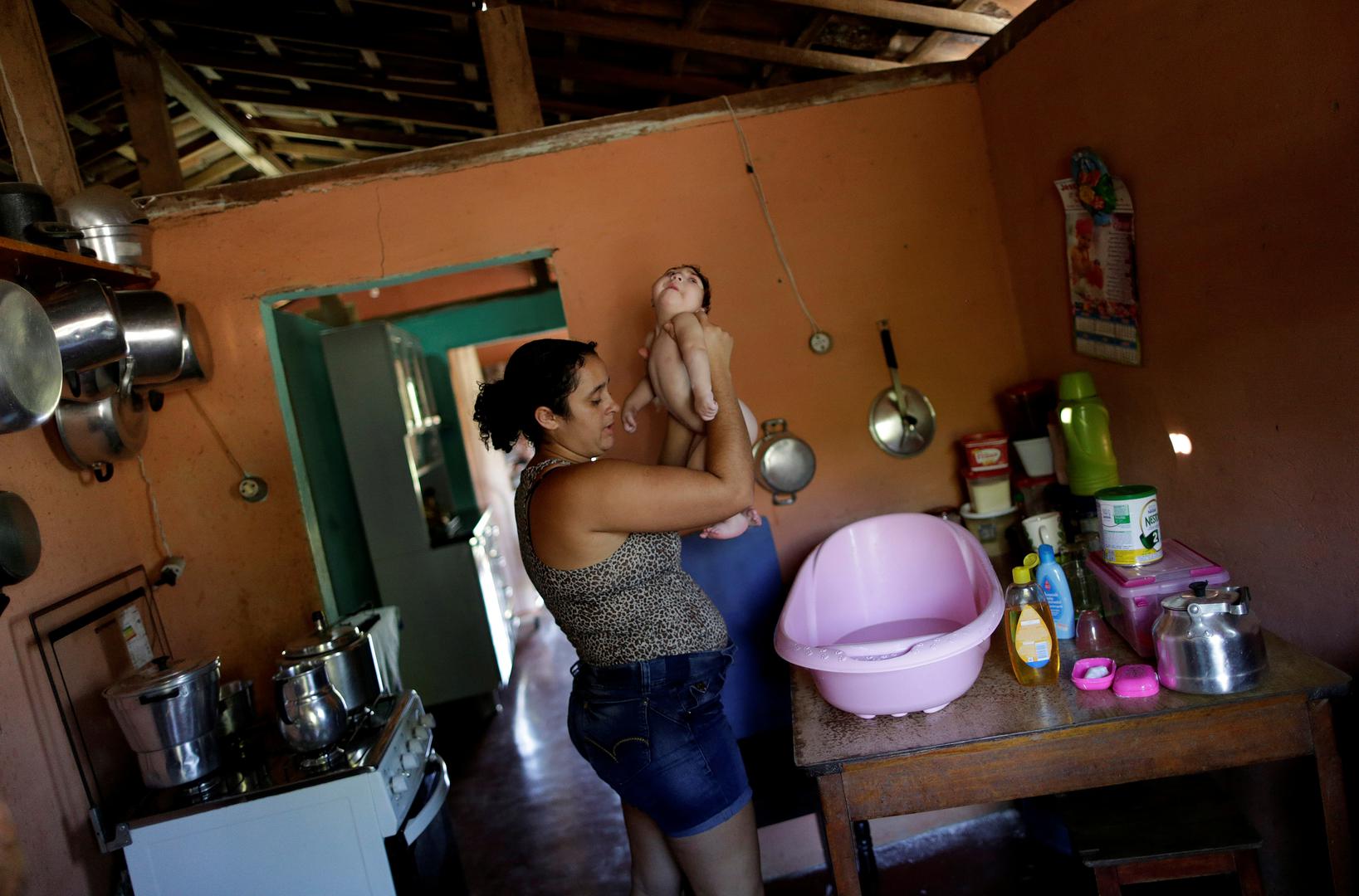 Raquel bathes her daughter Heloisa, a girl with Zika syndrome born in April 2016. Raquel says she cannot afford the medicines her twin daughters need for convulsions. 