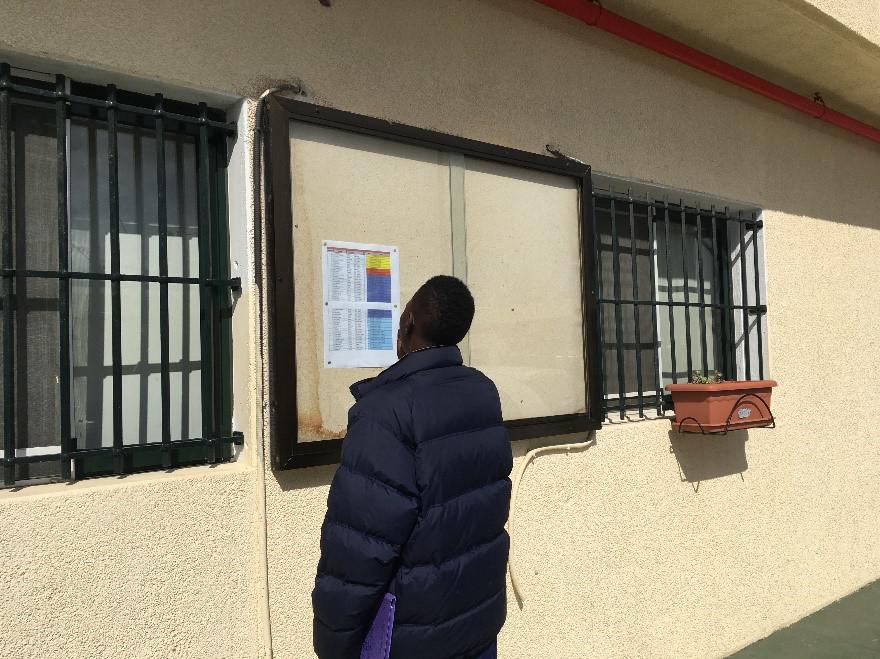 Migrantes buscan en la lista los nombres de las personas que se trasladarán de Ceuta a España peninsular, marzo de 2017.