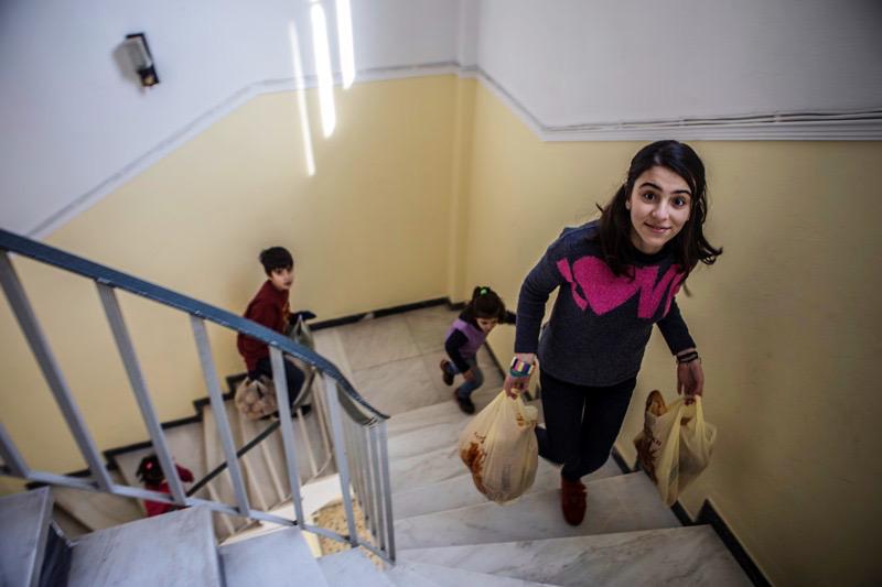 Lava and her siblings carry food donated by the local Catholic parish in Aigaleo, Greece. © 2017 Anna Pantelia