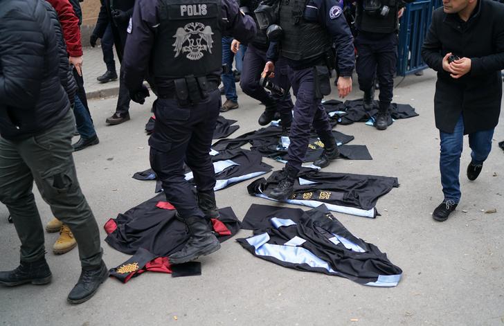 Turkish riot policemen walk over academic gowns laid down during a protest against the dismissal of academics from universities in the Cebeci campus of Ankara University