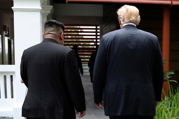 U.S. President Donald Trump and North Korea's leader Kim Jong Un walk together before their working lunch during their summit at the Capella Hotel on the resort island of Sentosa, Singapore June 12, 2018. Picture taken June 12, 2018. REUTERS/Jonathan Erns
