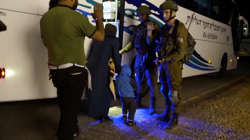 People walk past Israeli soldiers as they board a bus during the Syria Civil Defence, also known as the White Helmets, extraction from the Golan Heights in this still image taken from video, provided by the Israeli Army July 22, 2018.
