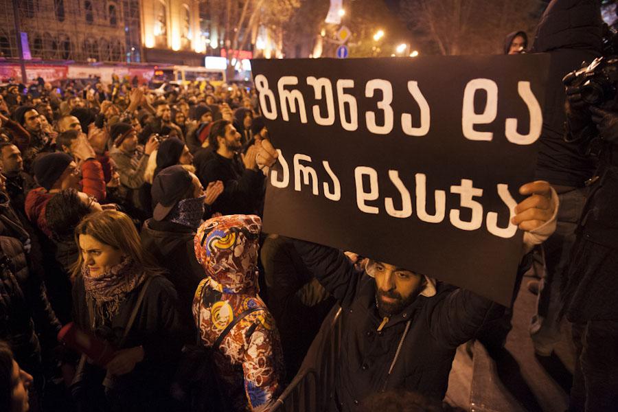 A sign which reads “Care instead of Punishment” is held aloft at a protest rally calling for decriminalization of personal drug use.