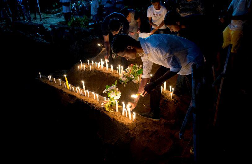 Relatives light candles after burial of three victims of the same family, who died at Easter Sunday bomb blast at St. Sebastian Church in Negombo, Sri Lanka, Monday, April 22, 2019.