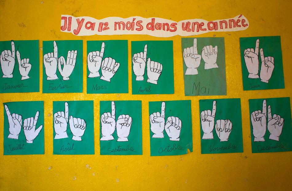 The names of the months in French and sign language are depicted inside a classroom for deaf students in Leveque