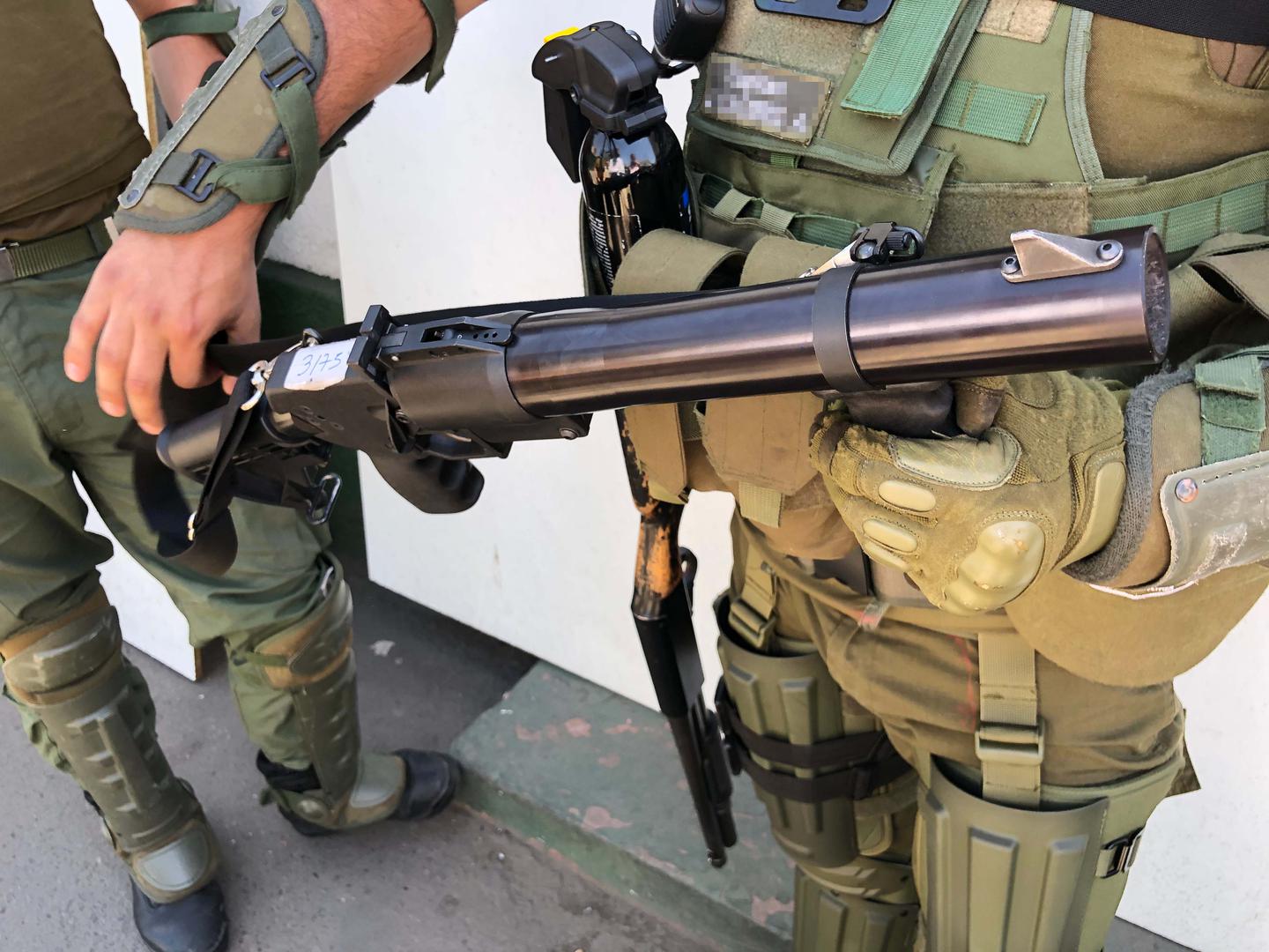 Um membro da polícia segura uma arma de gás lacrimogêneo. 